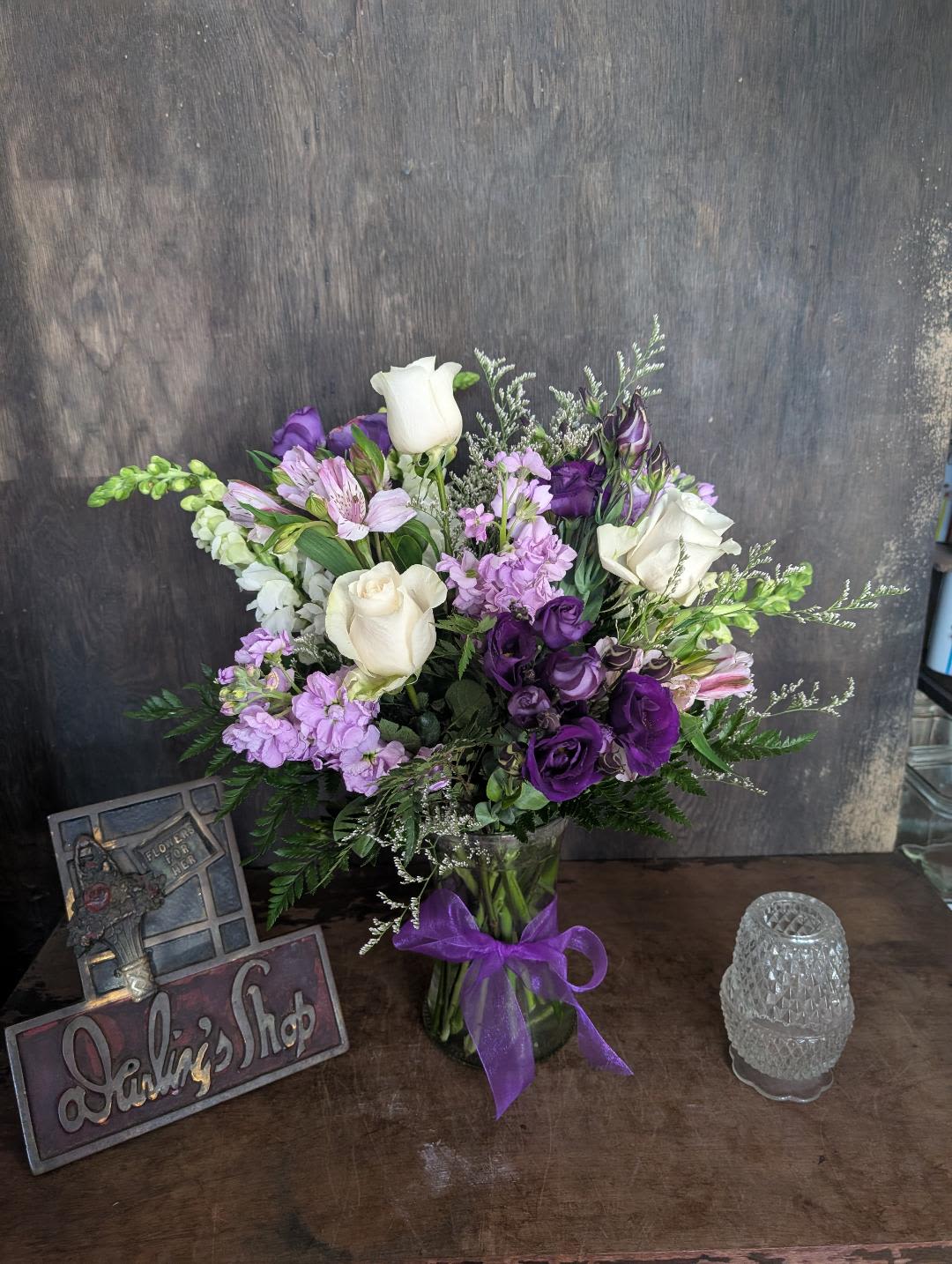 Purple and white bouquet in a glass vase with a ribbon
