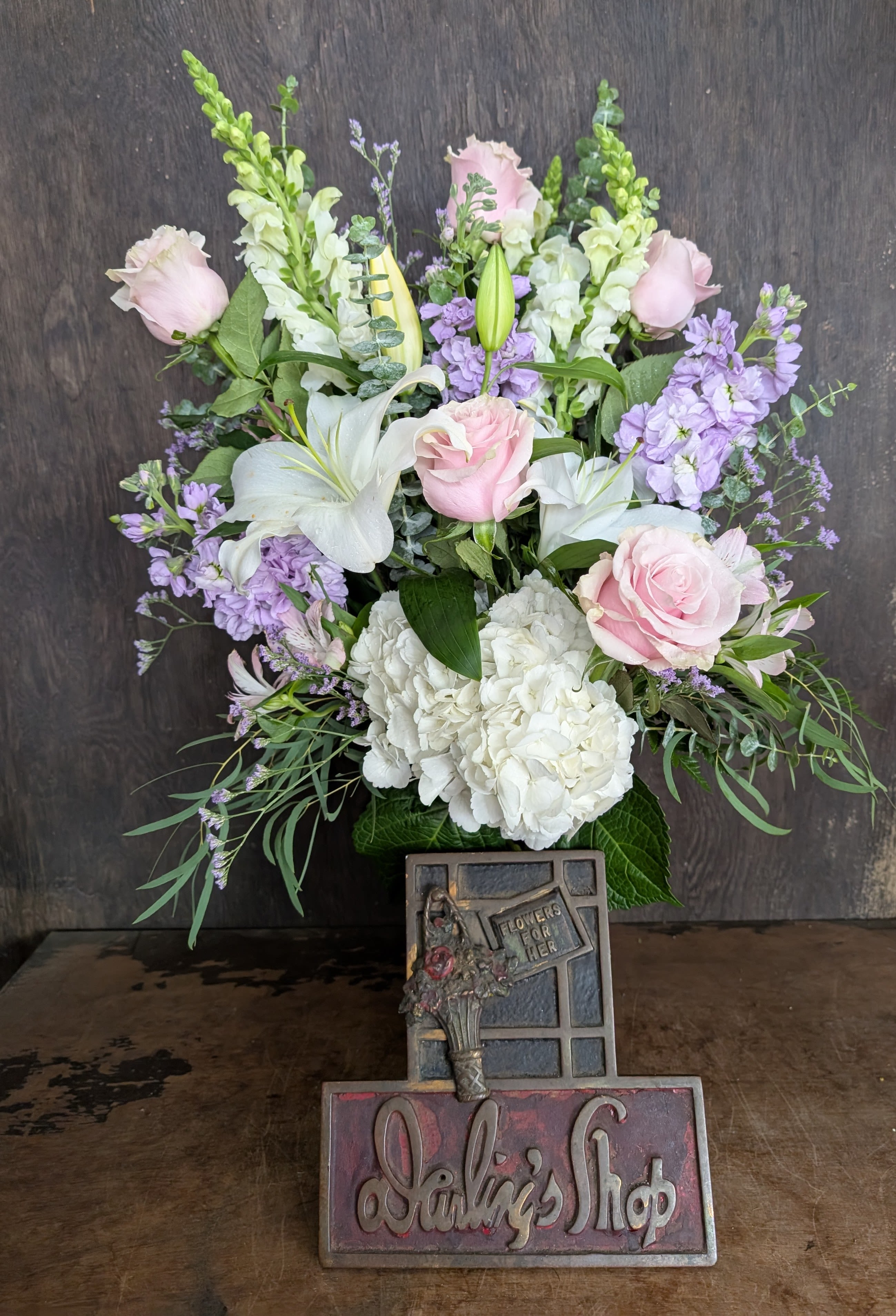 Bouquet of pink roses, white lilies, and lavender flowers in a vase