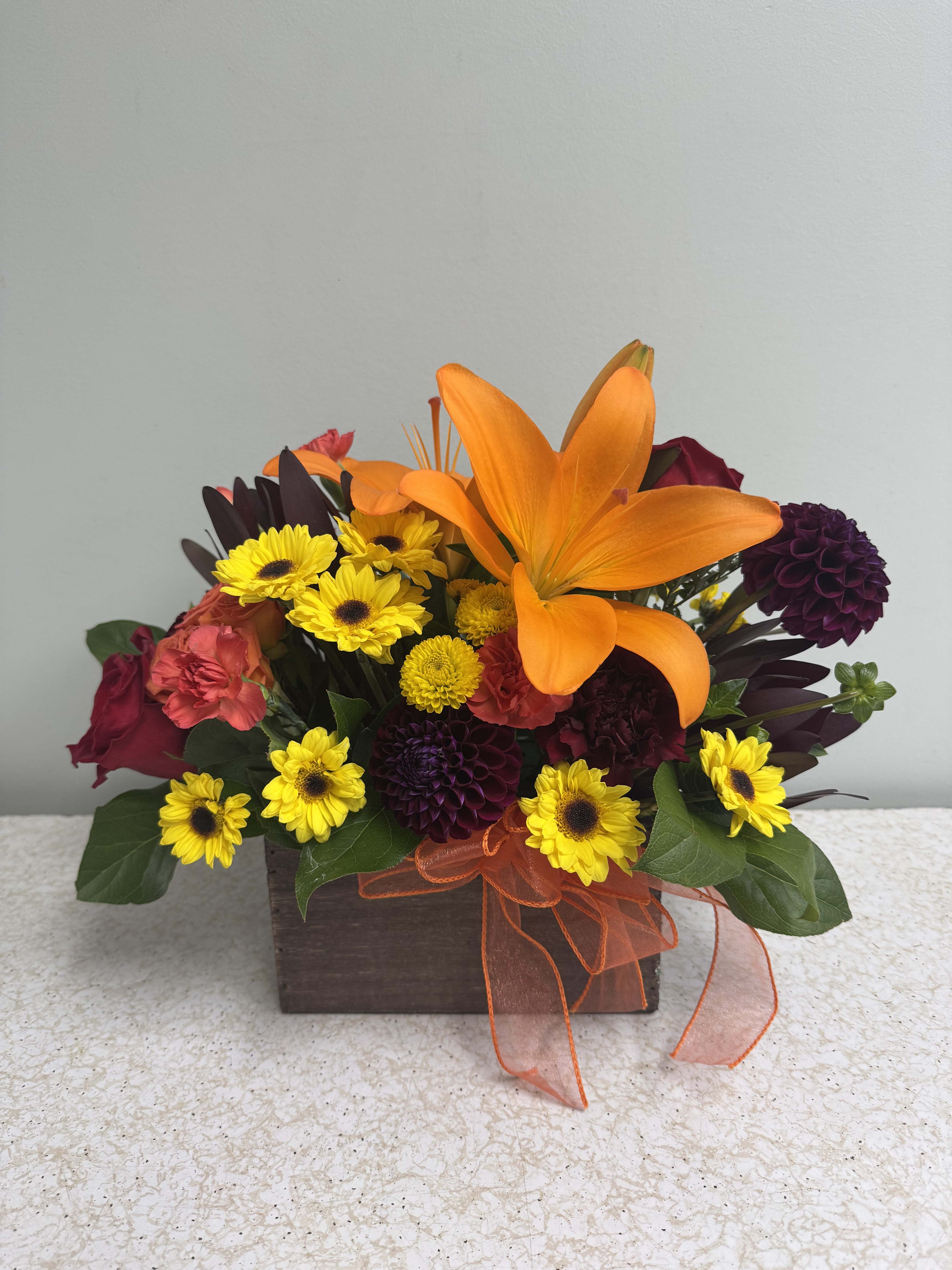 Orange lily and mixed yellow and burgundy flowers in a wooden box