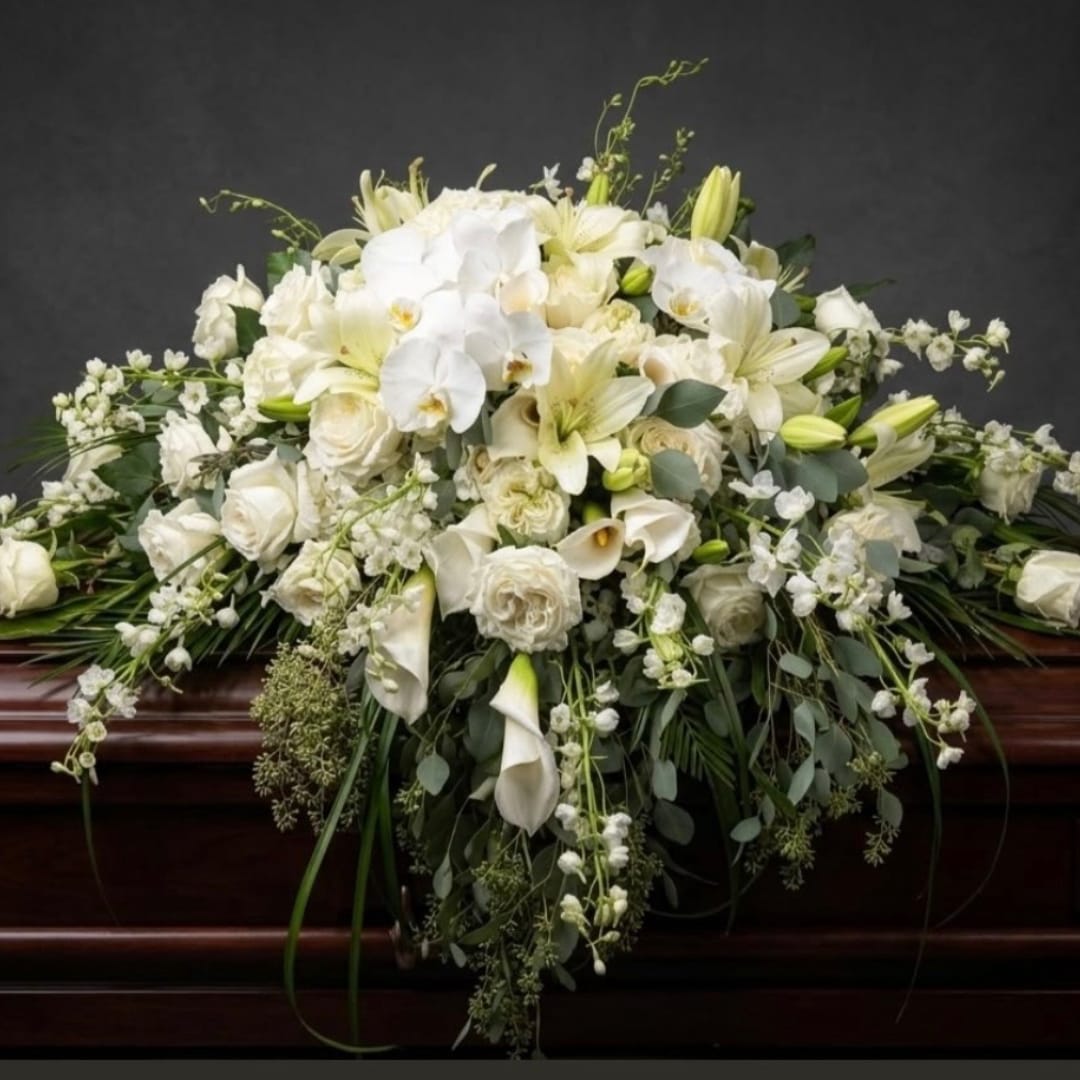 White floral casket spray with lilies, roses, and orchids