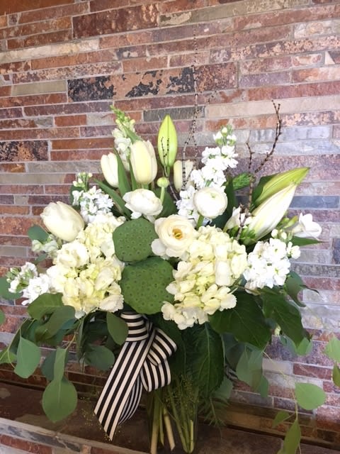 White floral arrangement with lilies, hydrangeas, and a striped ribbon