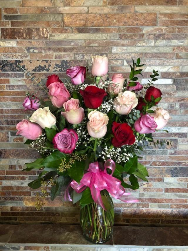 Bouquet of pink and red roses in a glass vase with a pink ribbon
