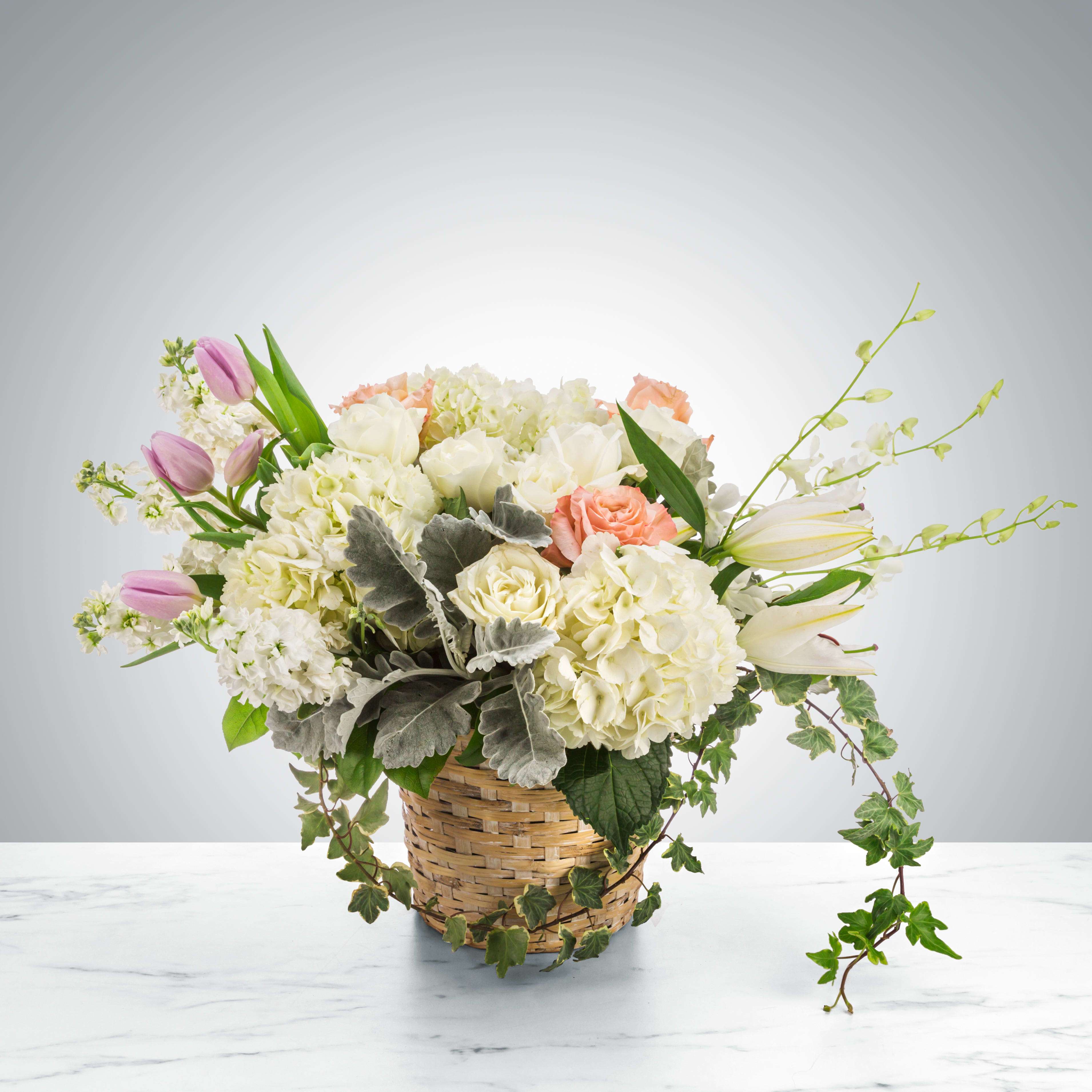 Basket arrangement with white and peach flowers and pink tulips