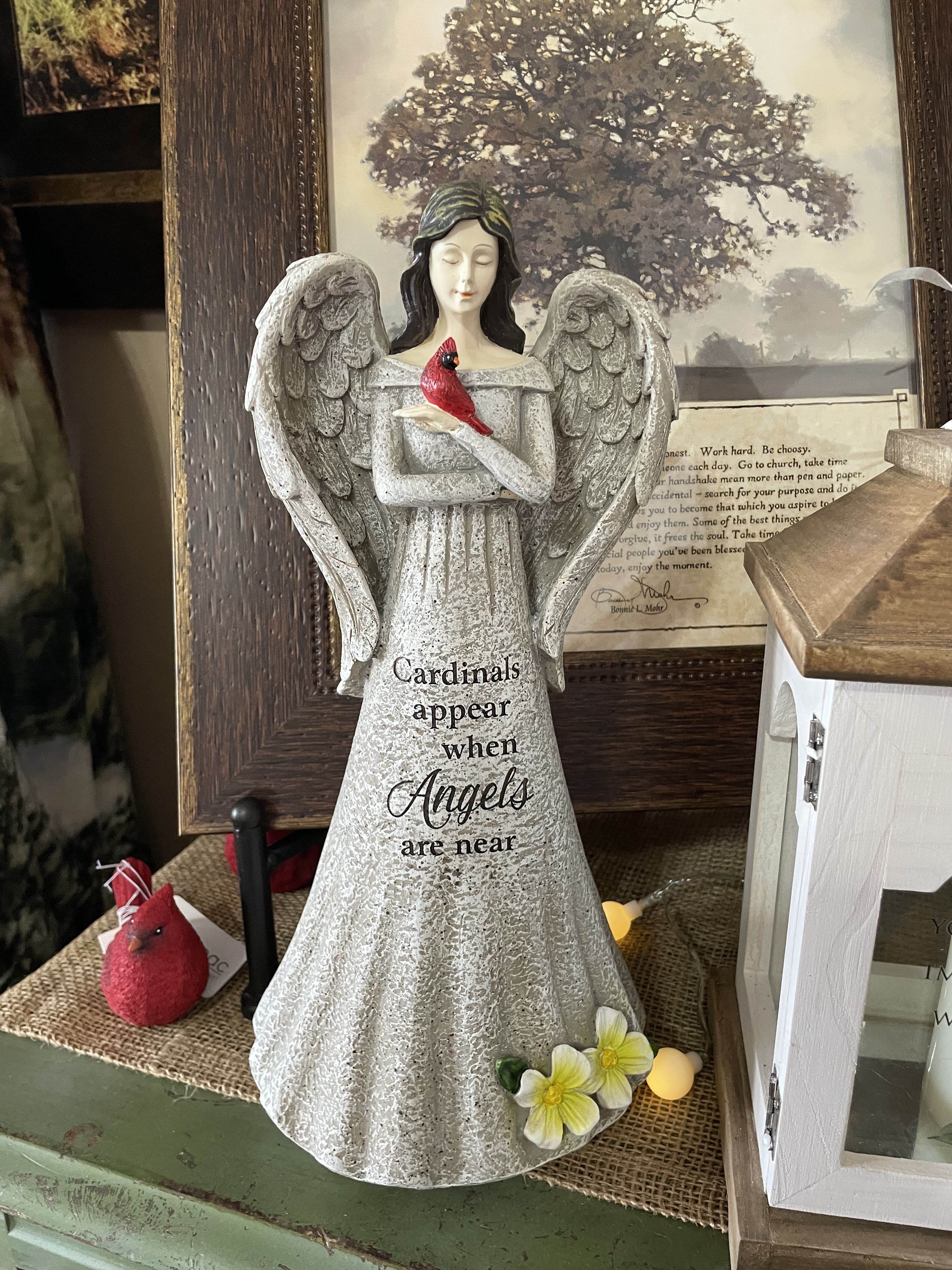 Angel figurine holding a red cardinal with small flowers at the base