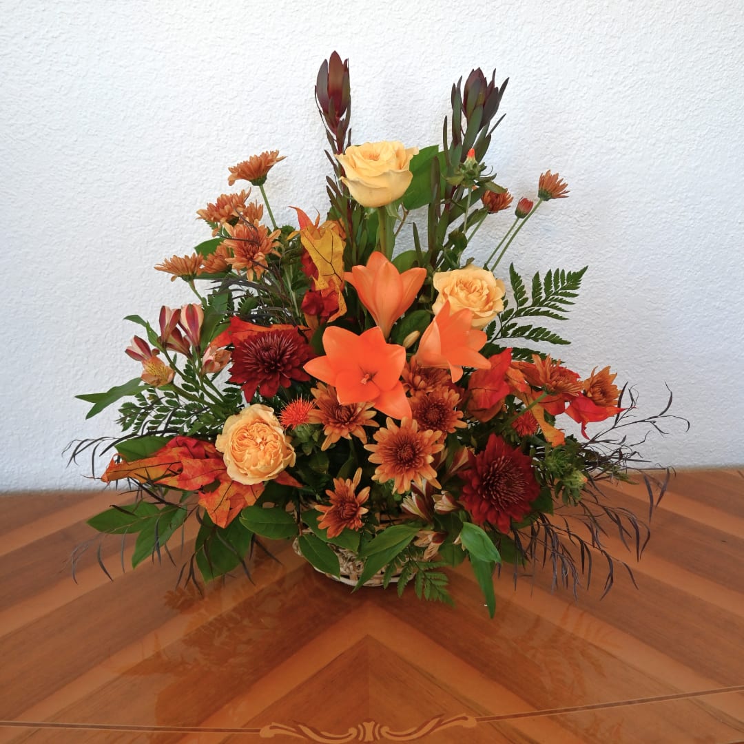 Autumn floral arrangement with orange and yellow blooms in a basket