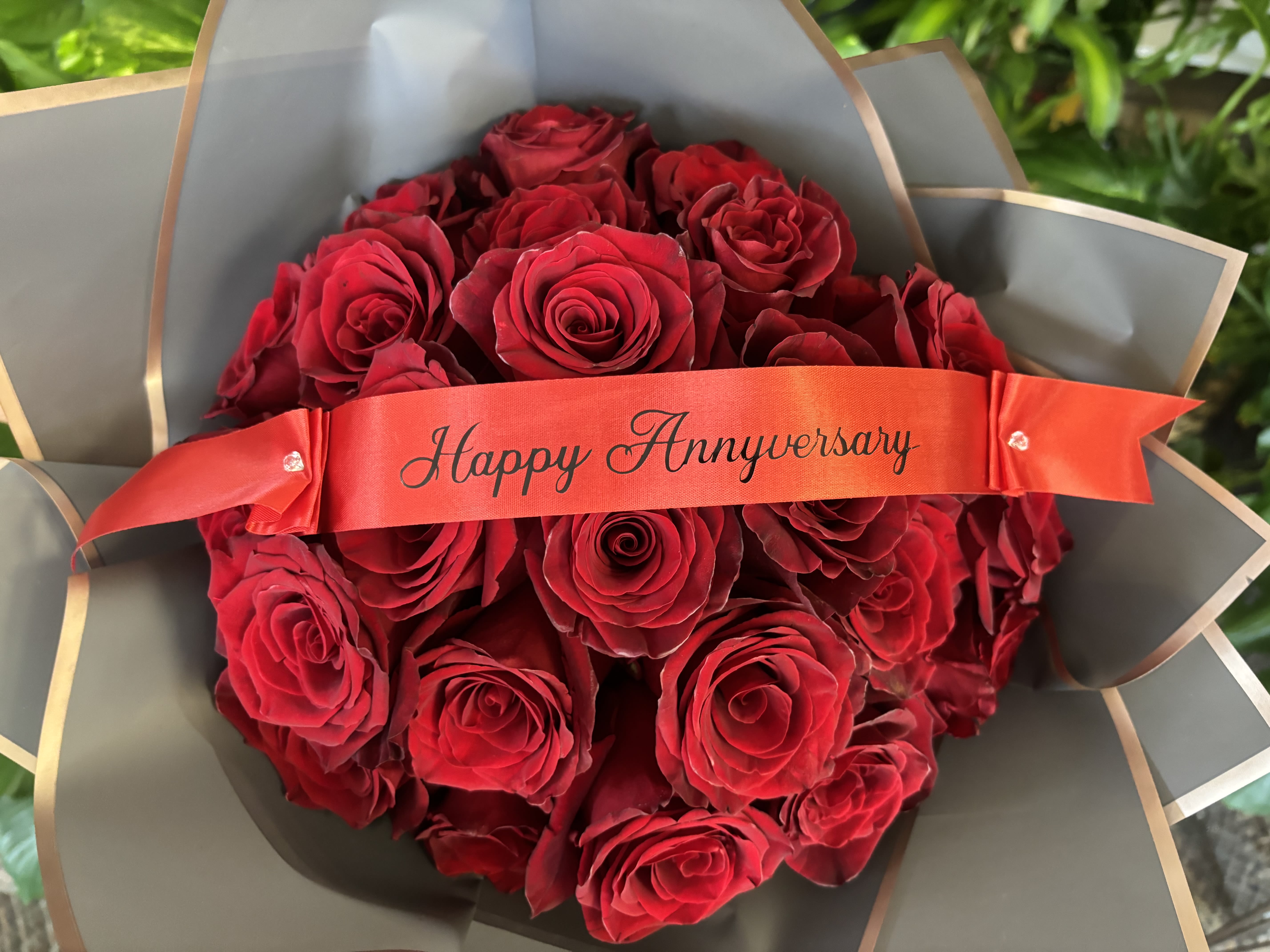 Bouquet of red roses wrapped with a Happy Anniversary ribbon