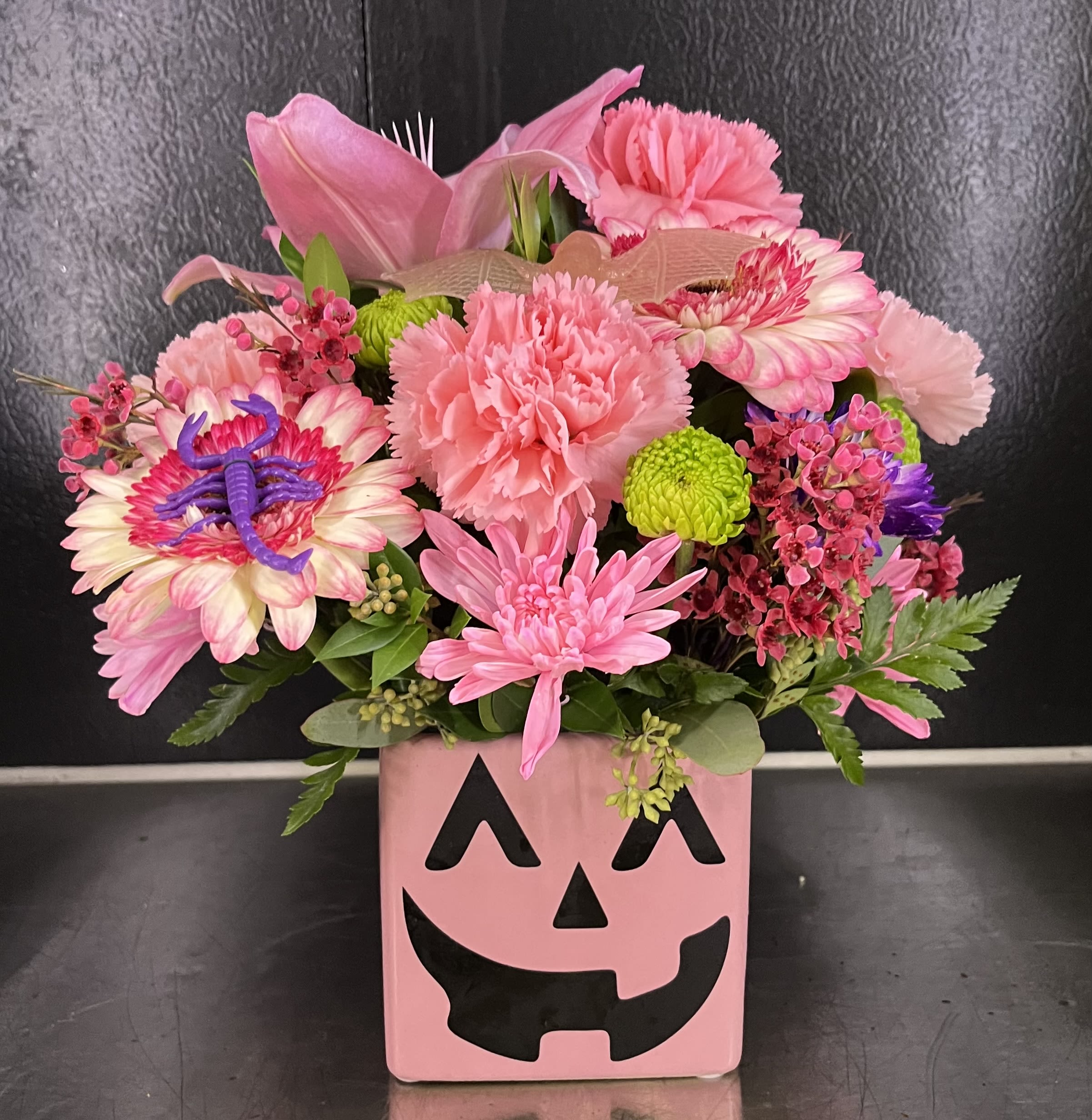 Pink floral arrangement in a jack-o'-lantern vase