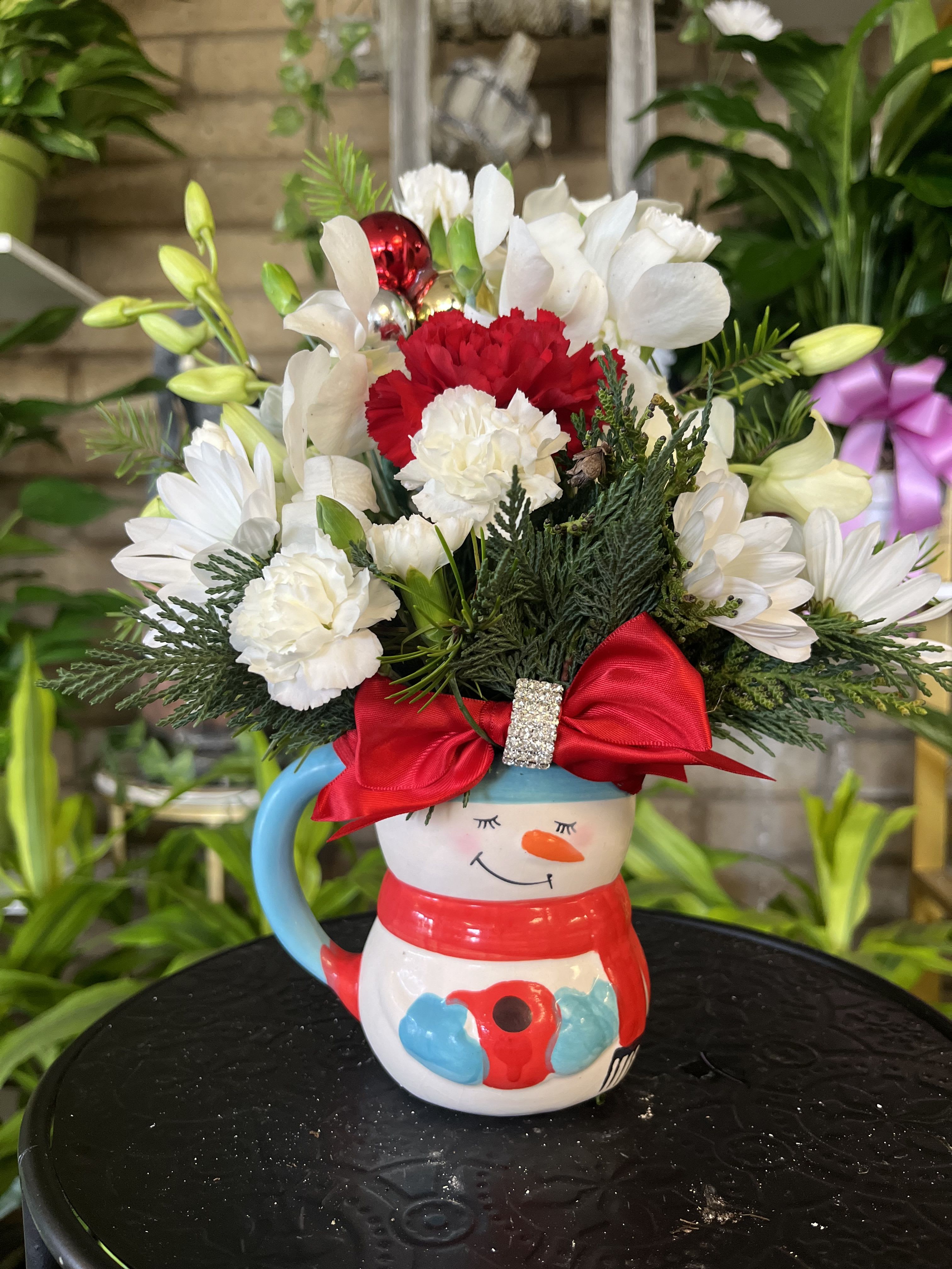 Snowman mug filled with white and red flowers and a red bow