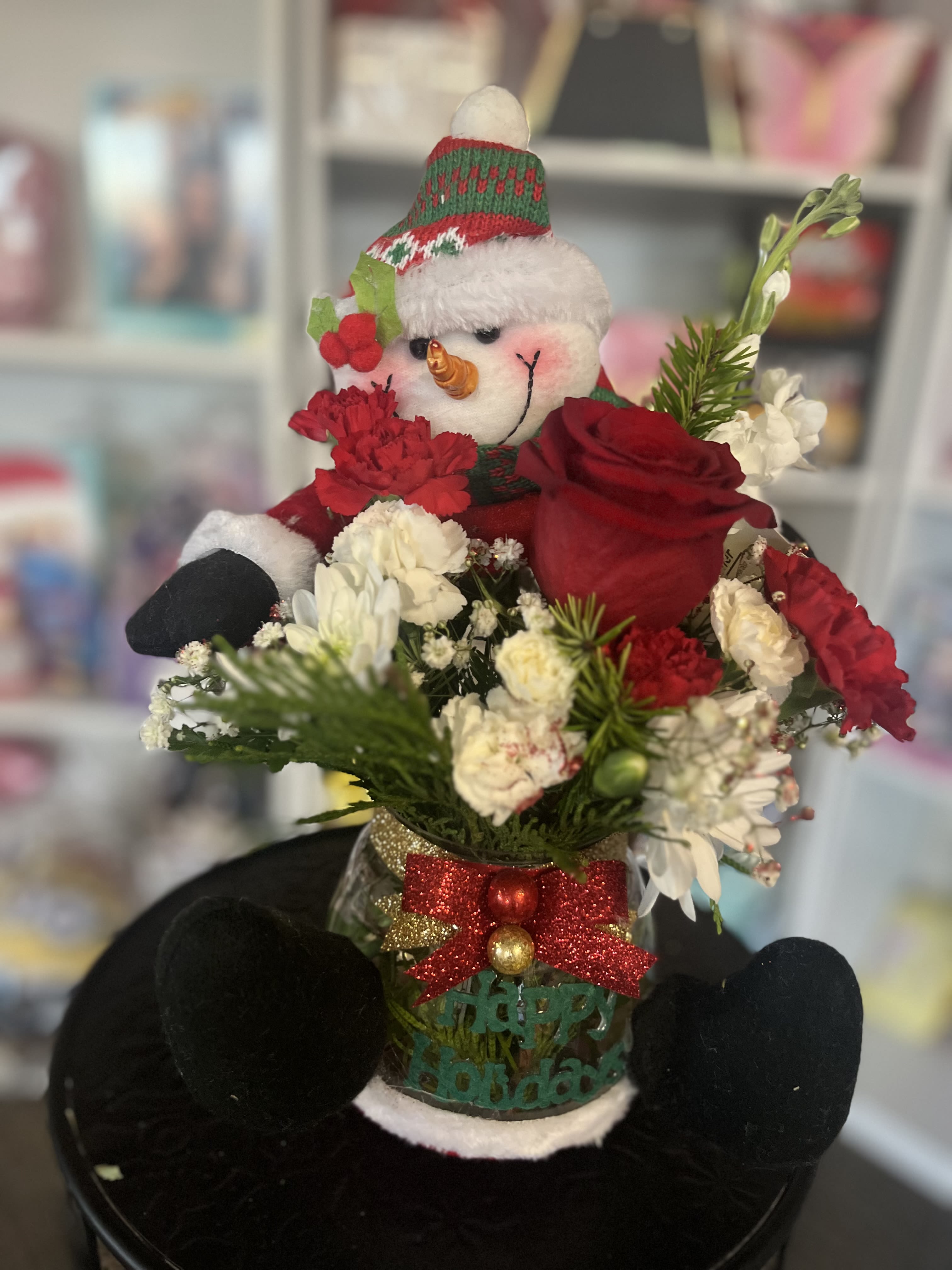 Snowman figurine in a holiday flower arrangement with red and white blooms