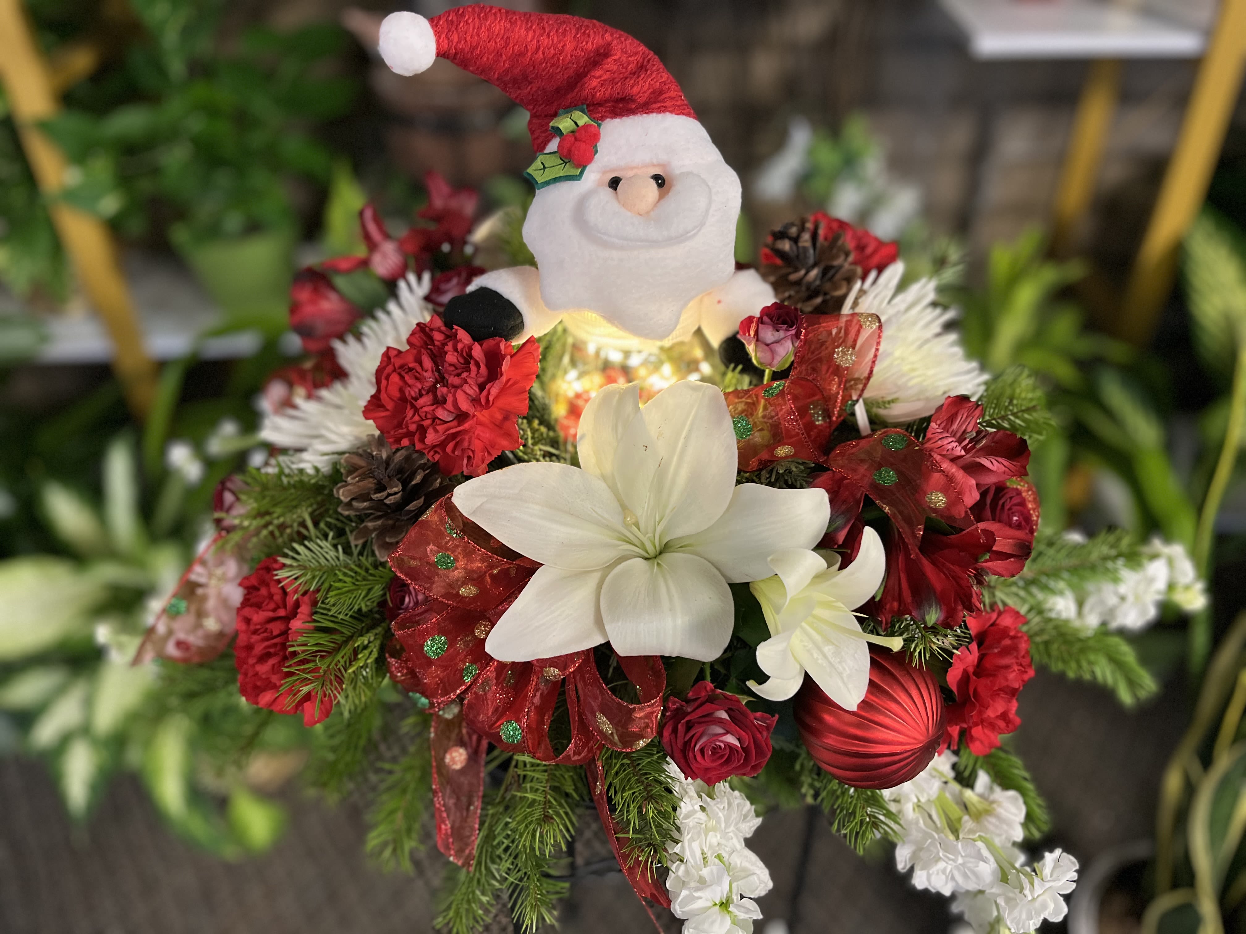 Christmas bouquet with a Santa plush, white lilies, red carnations, and ribbon