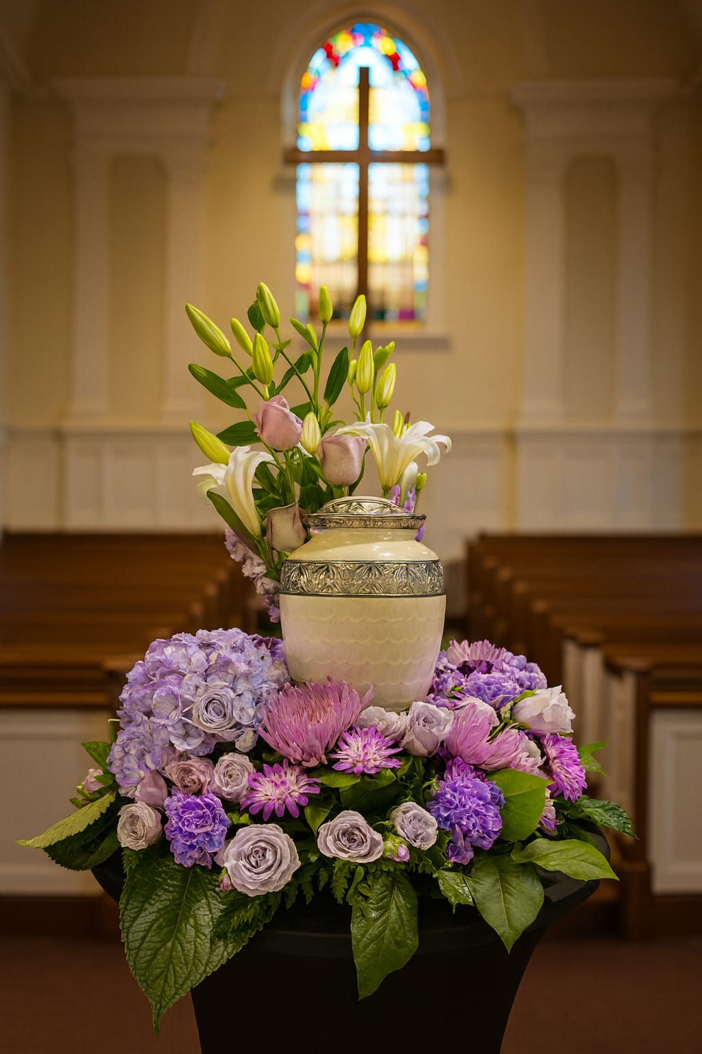 Purple and white floral arrangement with lilies in a decorative urn