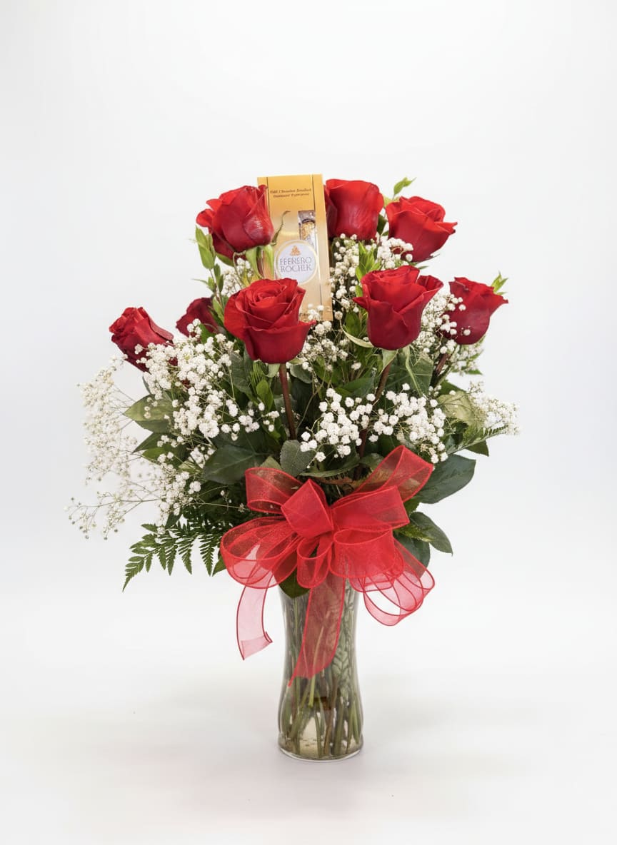 Red roses in a clear glass vase with a red bow and a chocolate box