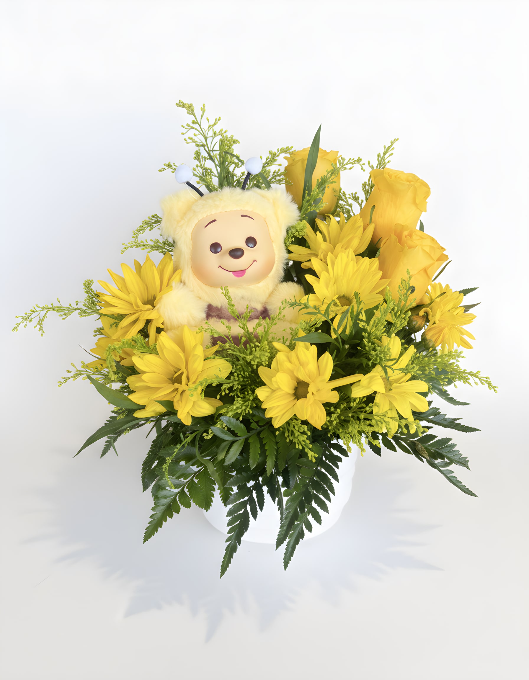 Yellow flower arrangement with a plush bear in a white vase