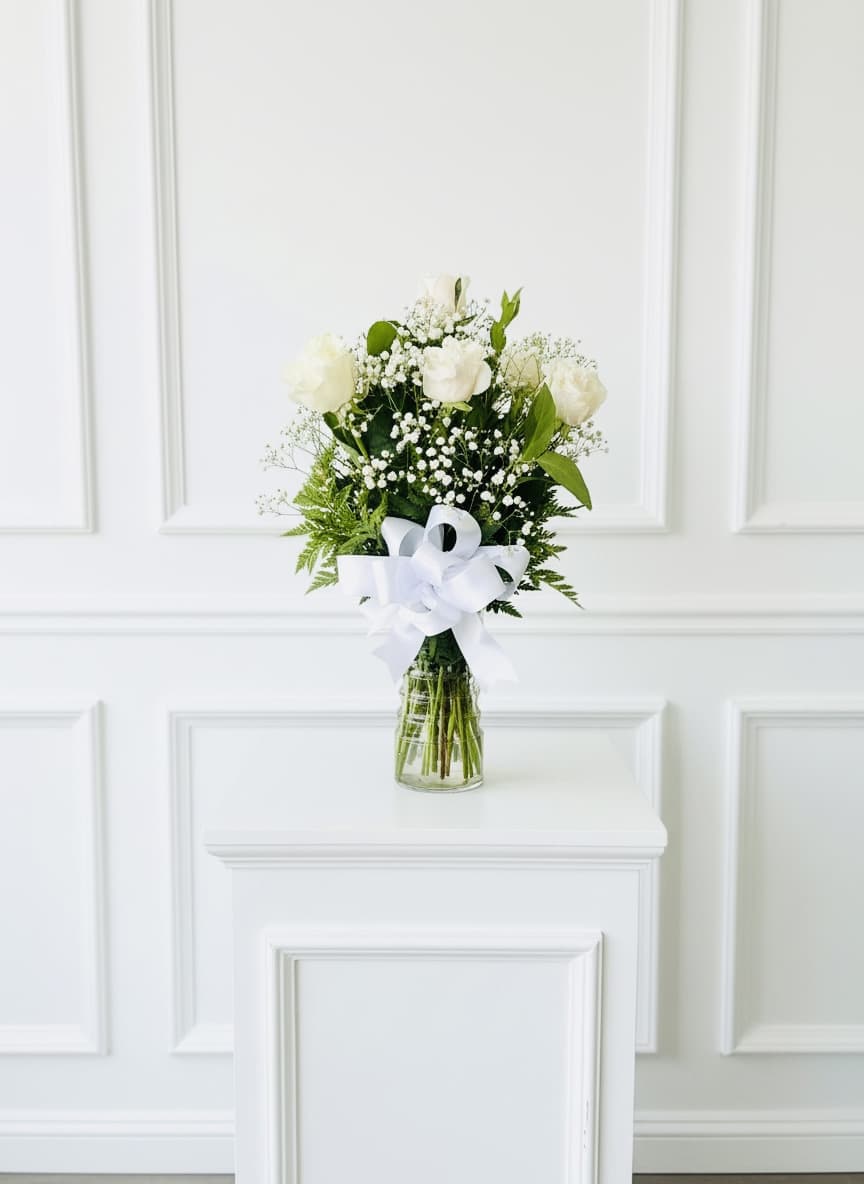 White rose bouquet in a glass vase with a white ribbon
