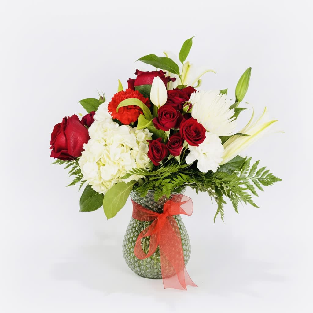 Red roses and white flowers in a glass vase with a red ribbon