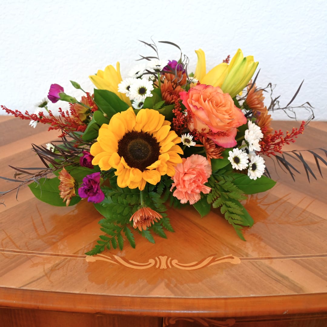 Mixed bouquet with a sunflower, peach roses, and small white daisies