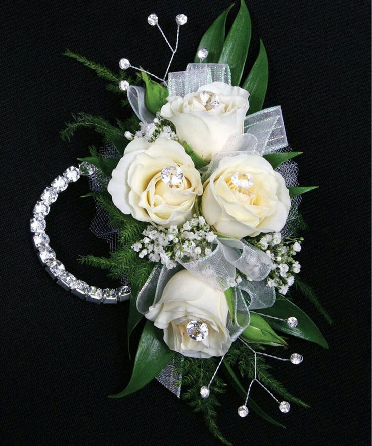 White rose corsage with silver ribbon and rhinestone accents on a black background