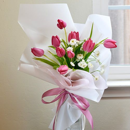 Whisper of Spring - ***** If you prefer flowers in a different color palette, please indicate your preference in the special instructions box.*****  A tulip bouquet is a vibrant and enchanting arrangement of tulip flowers, renowned for their elegance and charm. Typically, these bouquets feature a variety of tulip colors, ranging from vibrant reds, yellows, and oranges to delicate pinks, purples, and whites, each adding its own unique flair to the ensemble.  Tulips are known for their simple yet striking appearance, with slender stems and bold, cup-shaped blooms. Their petals can be smooth and glossy, with a slight sheen that adds to their allure. Depending on the arrangement, the bouquet may showcase tulips of uniform color for a clean and sophisticated look, or it might incorporate a mix of hues for a more dynamic and lively display.  A tulip bouquet exudes a sense of freshness and vitality, making it a popular choice for various occasions, from weddings and birthdays to anniversaries and celebrations of all kinds. Whether presented as a romantic gesture or as a token of appreciation, a tulip bouquet never fails to captivate with its beauty and simplicity.