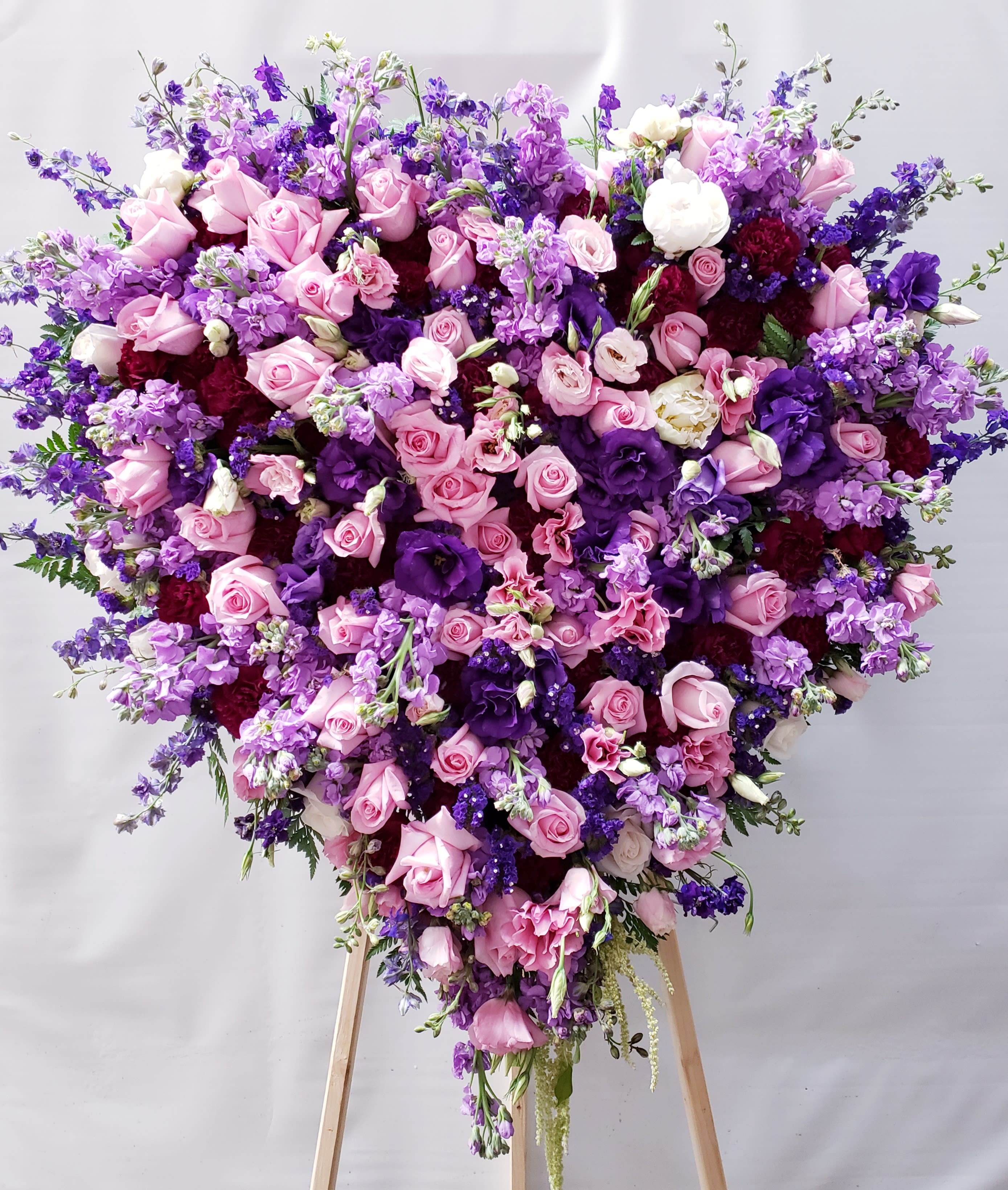 Heart-shaped bouquet of pink and purple flowers on a stand
