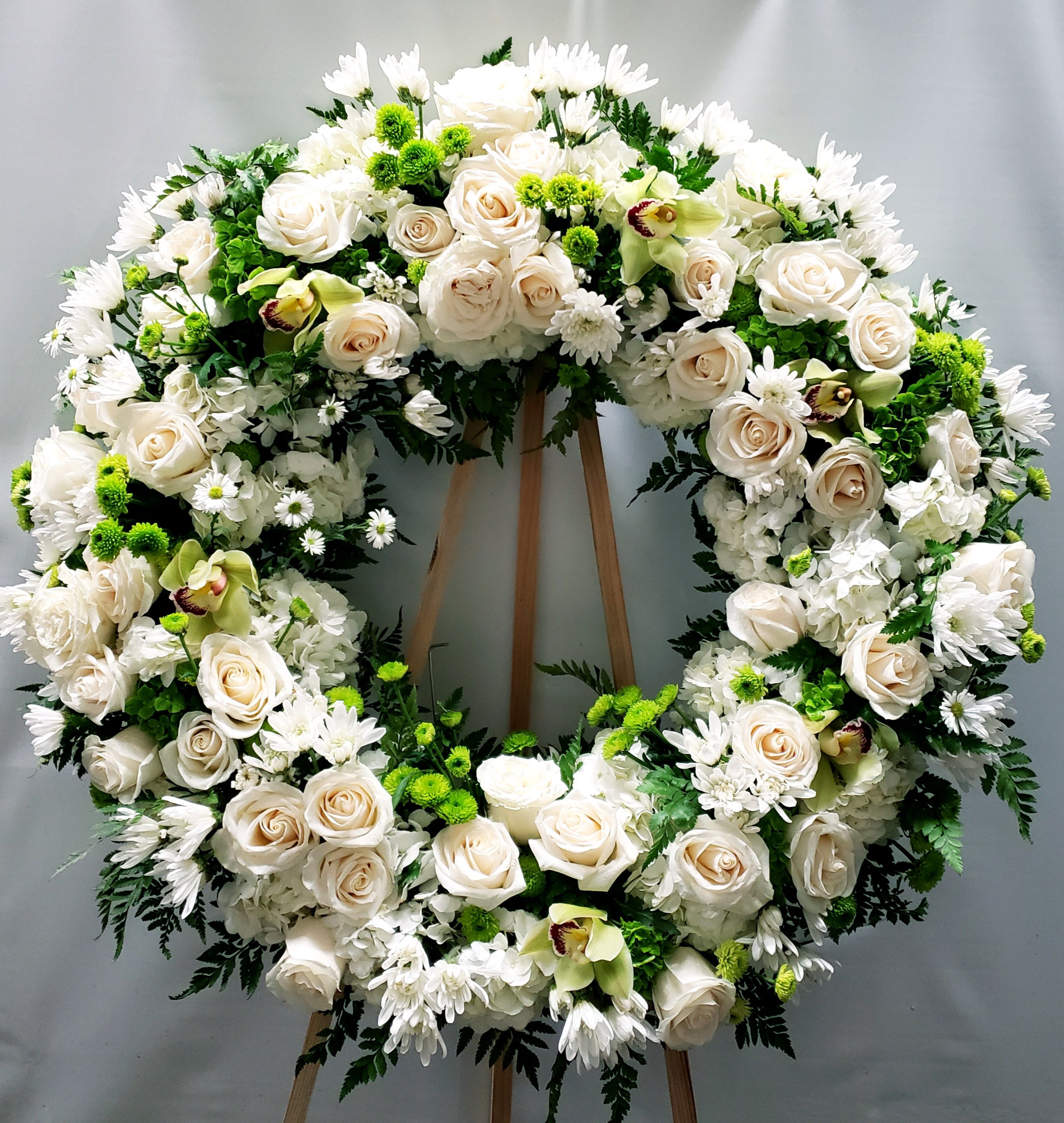 Large white floral wreath on a wooden stand