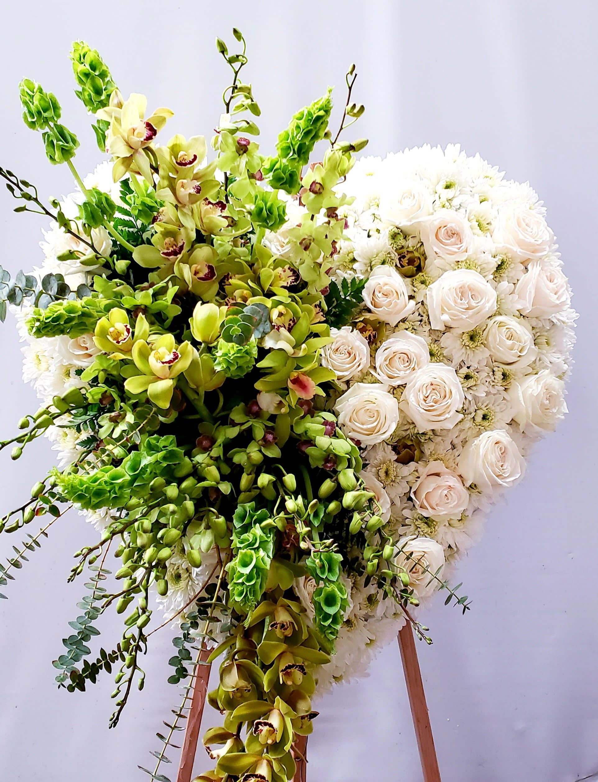 Large floral standing spray with white roses and green orchids on an easel