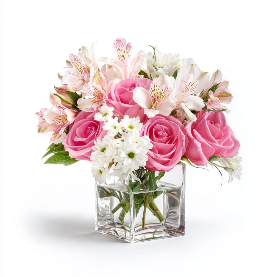 Pink roses and white flowers arranged in a clear square vase