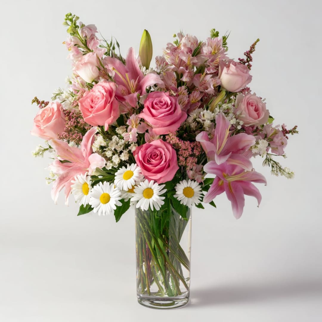 Pink roses and lilies arranged in a clear glass vase with white daisies