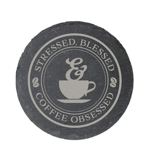 Round slate coaster with a coffee cup graphic and text