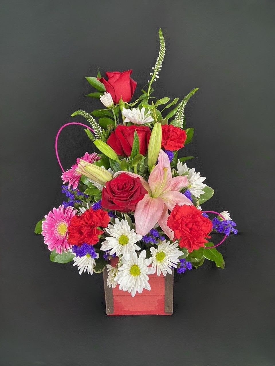 Crate Of Love - Show someone special exactly how much you love them with this decorative wooden crate overflowing with lovely roses, lilies, gerbera daisies, carnations, daisies, veronica, and stars of Bethlehem (when available) and is accented with pink swirls.