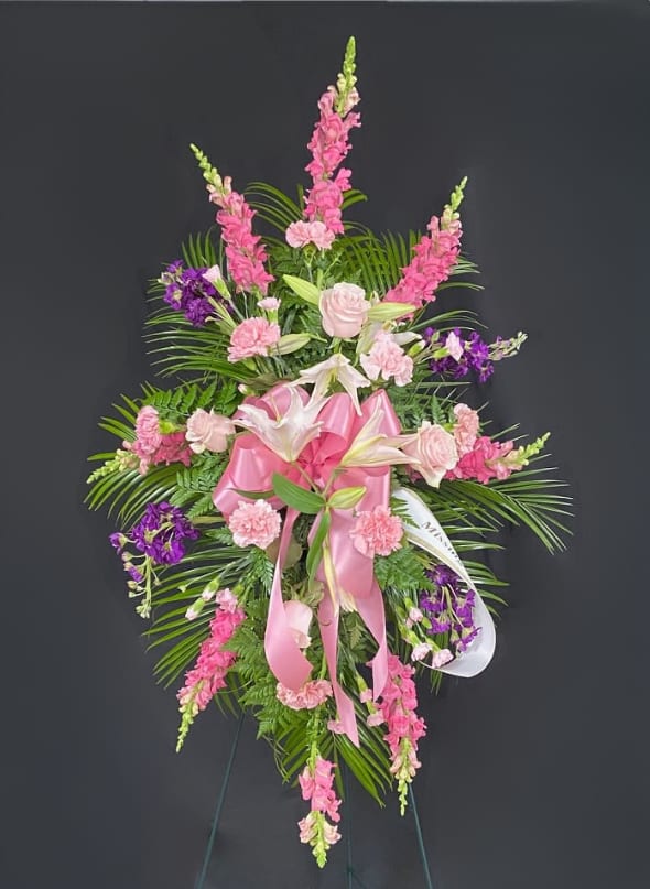Pink and purple funeral spray with lilies and roses on a stand