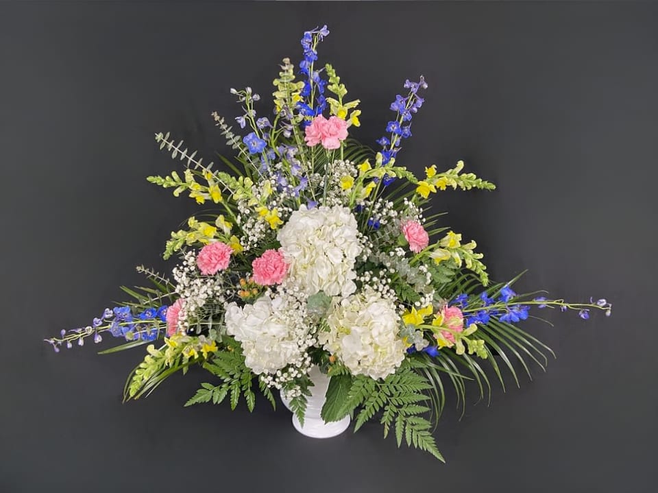 Memories of You Funeral Basket - Always remember the good times and fond memories of a life beautifully lived. Celebrate those times with our Memories of You Funeral Basket arrangement. Made up of white hydrangeas, blue delphinium, yellow snapdragons, pink carnations, and filled with baby's breath.
