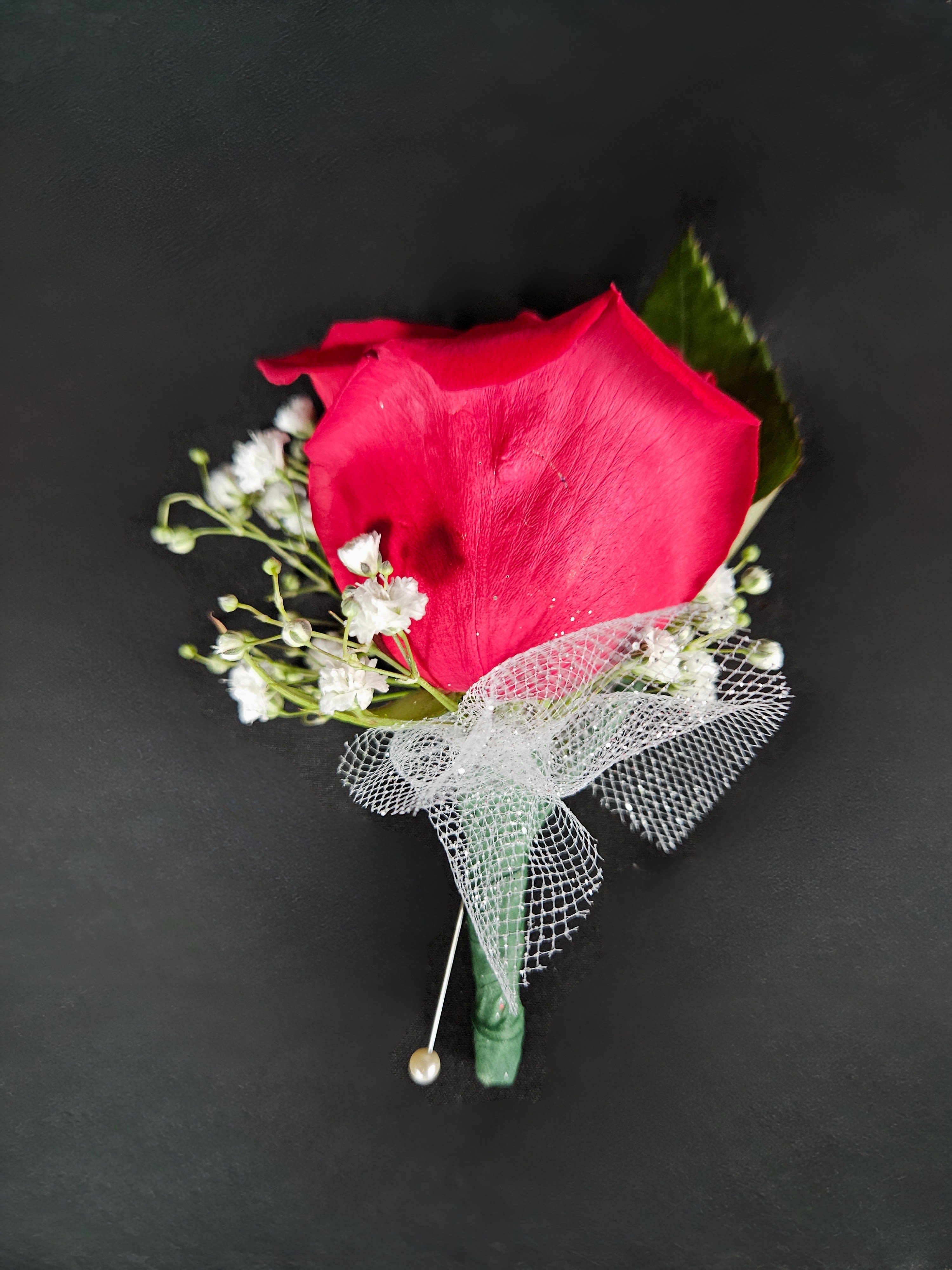 Single red rose boutonniere with white baby's breath and mesh ribbon