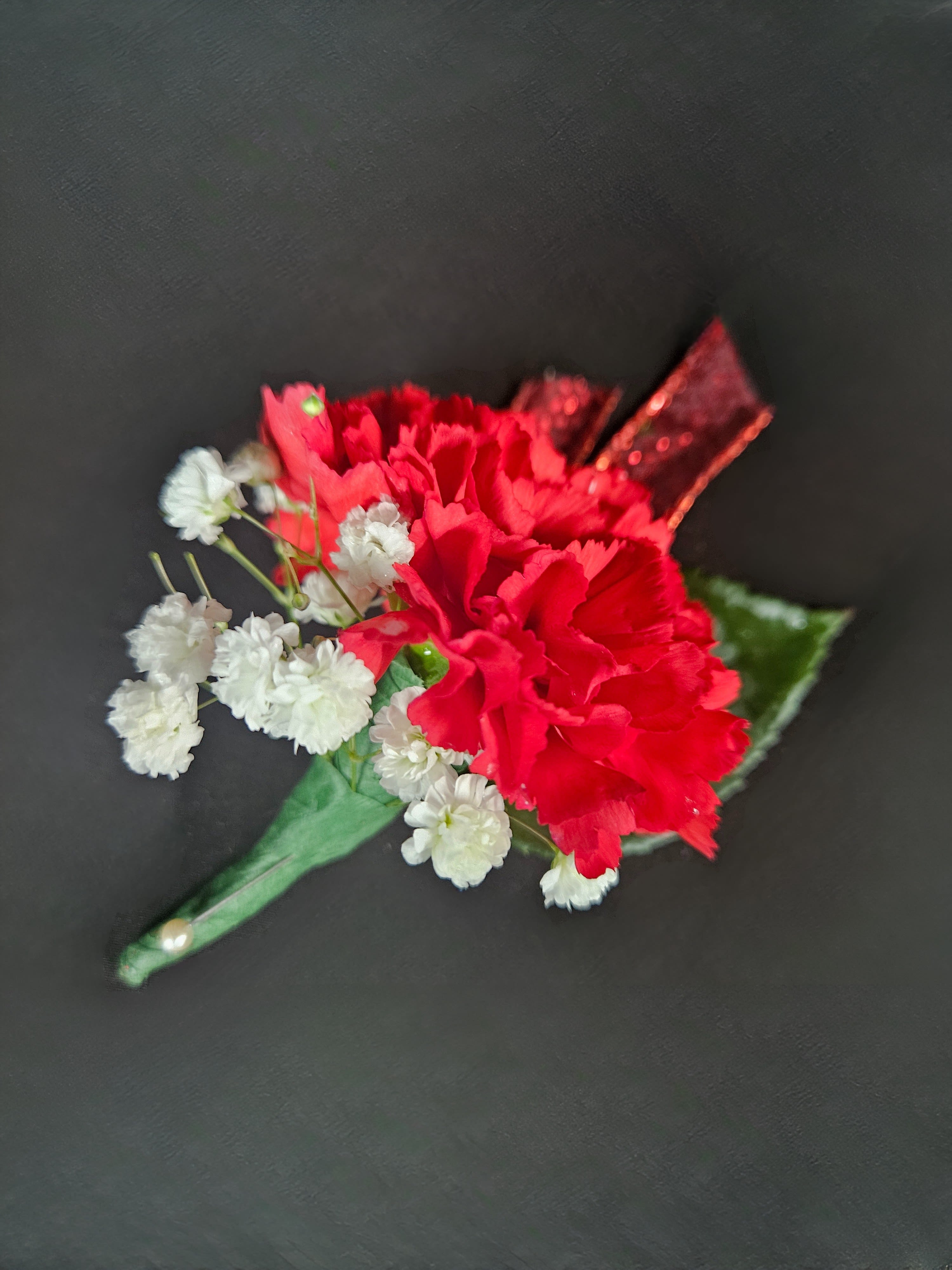 Red carnation boutonniere with white baby's breath on a green wrap