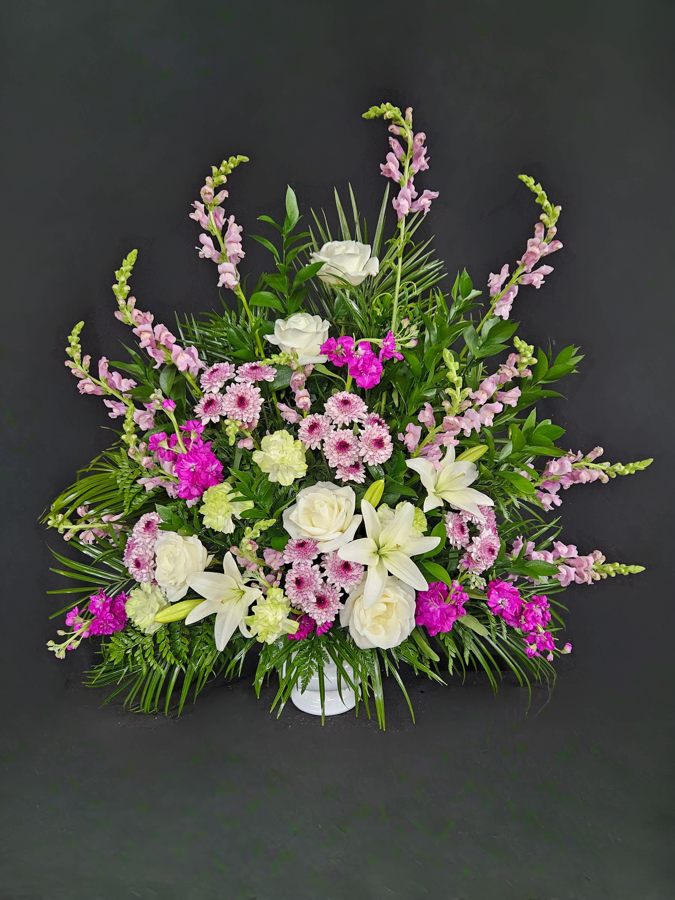 White lilies and roses with pink flowers in a white vase
