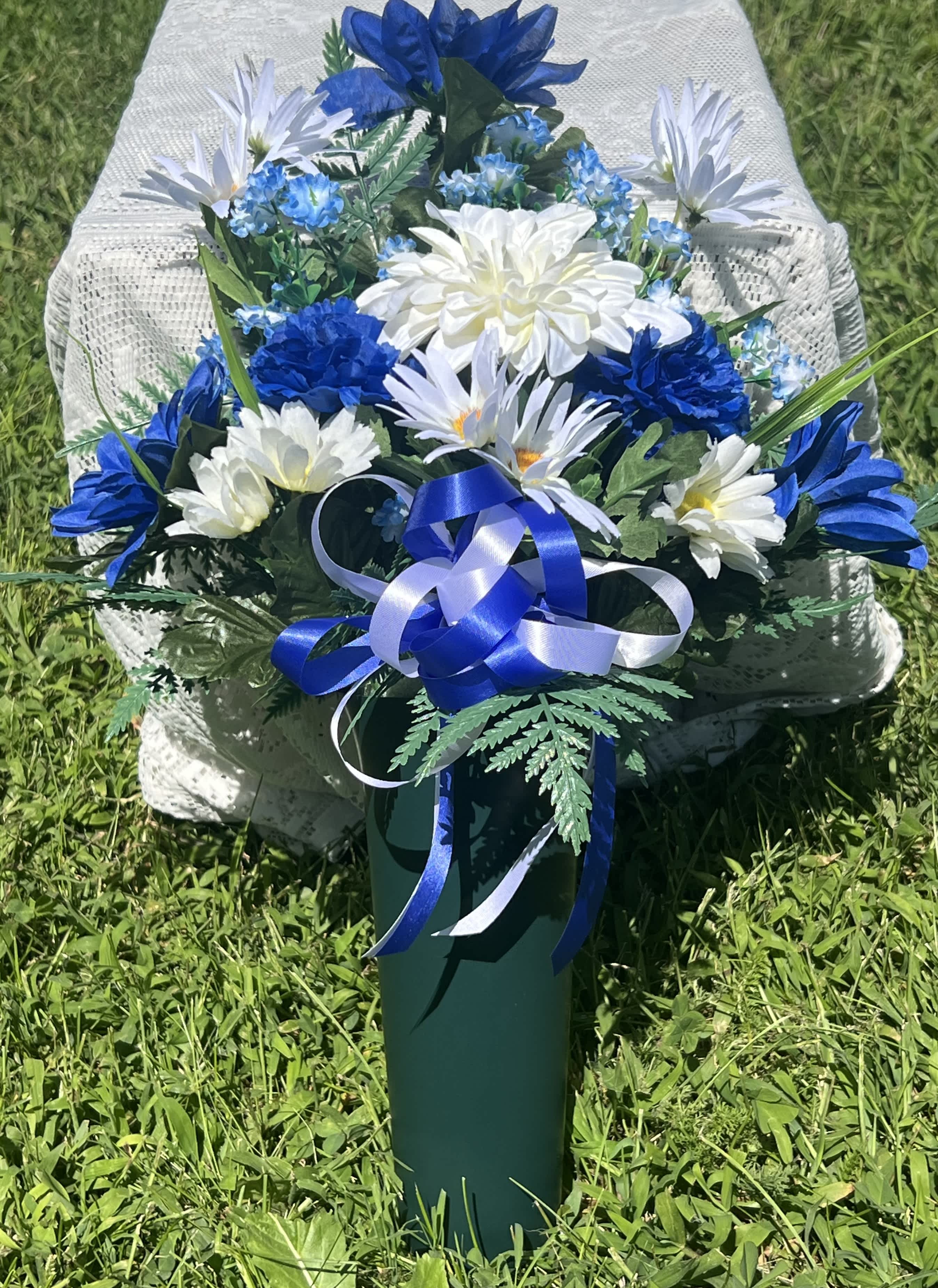 Blue and white flower arrangement in a green vase with ribbon