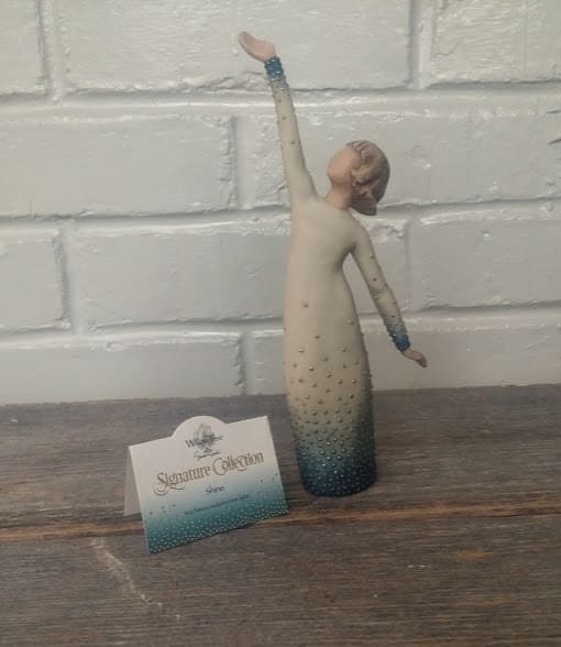 Decorative figurine of a woman in a long dress with one arm raised