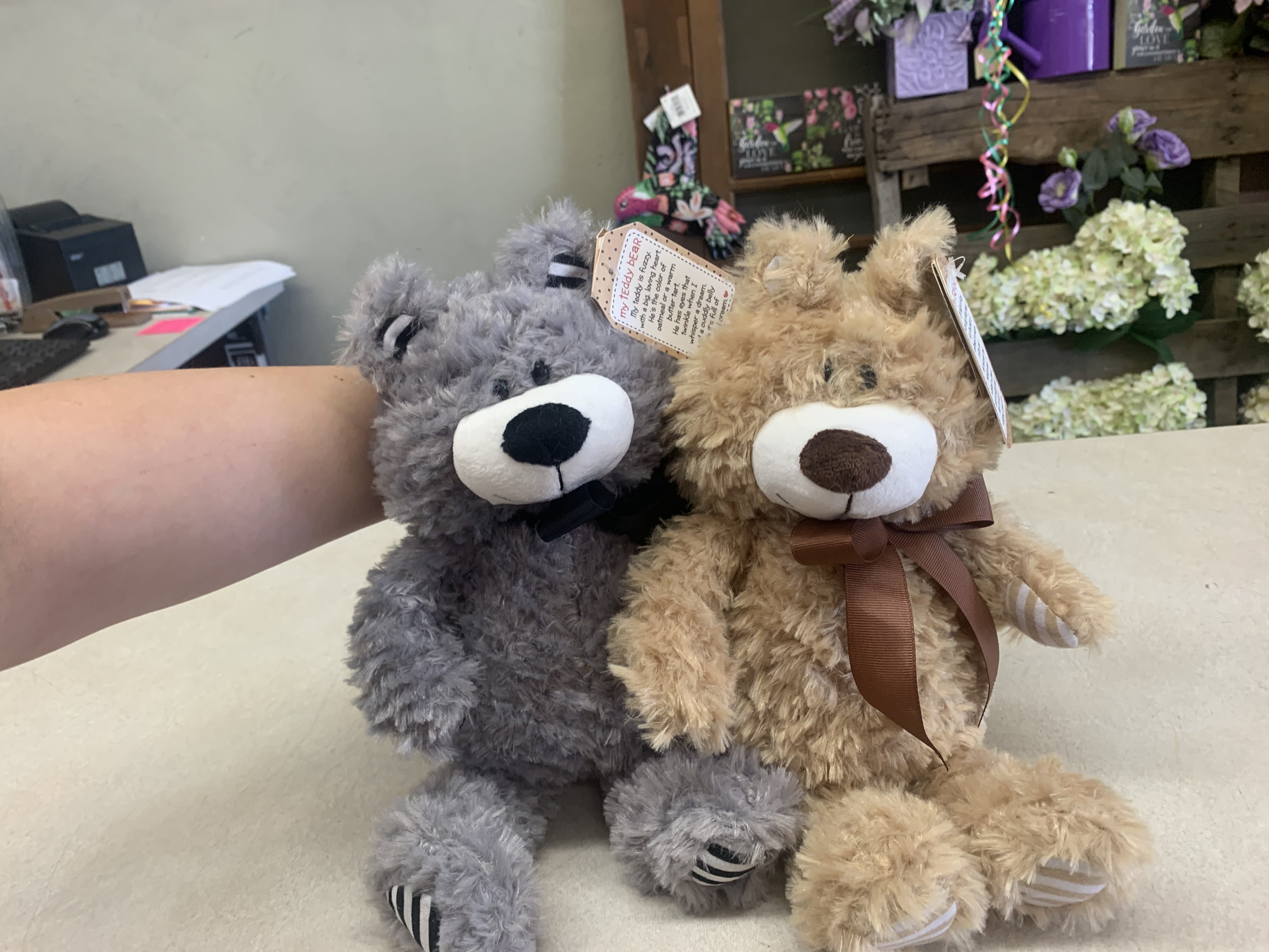 Two plush teddy bears sitting side by side on a counter.
