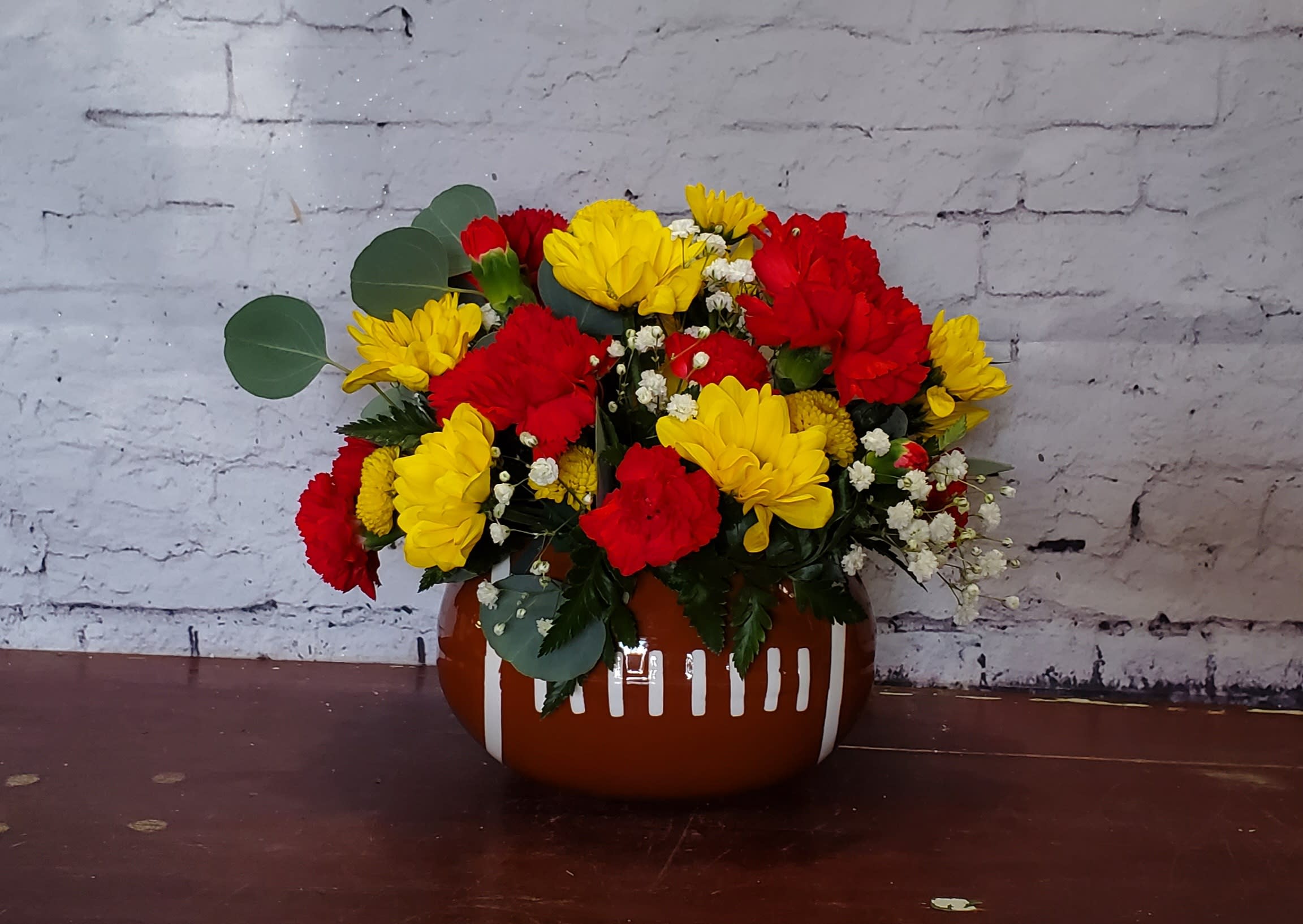 Red and yellow flower arrangement in a brown ceramic vase