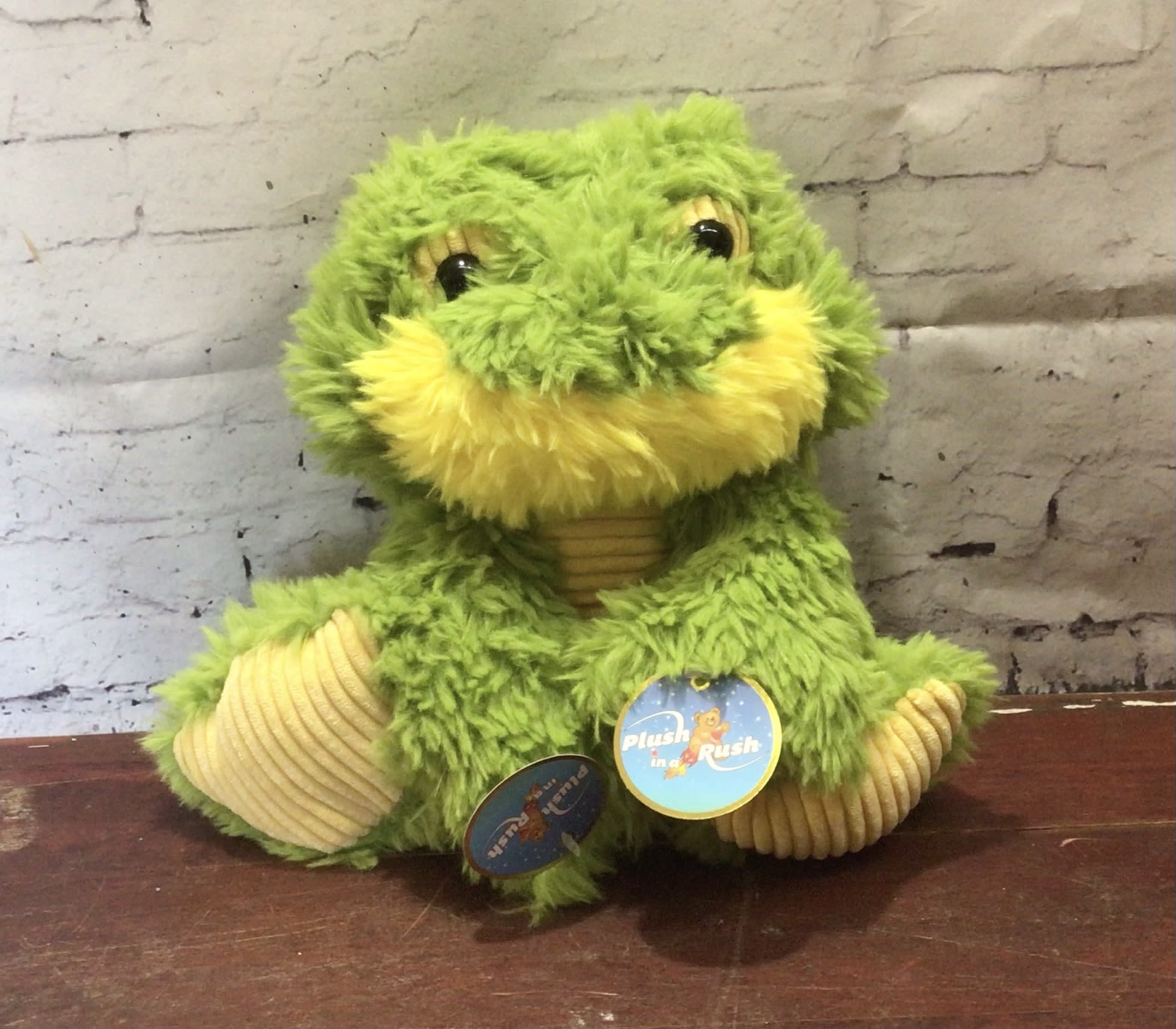 Green plush frog toy with yellow accents sitting on a table
