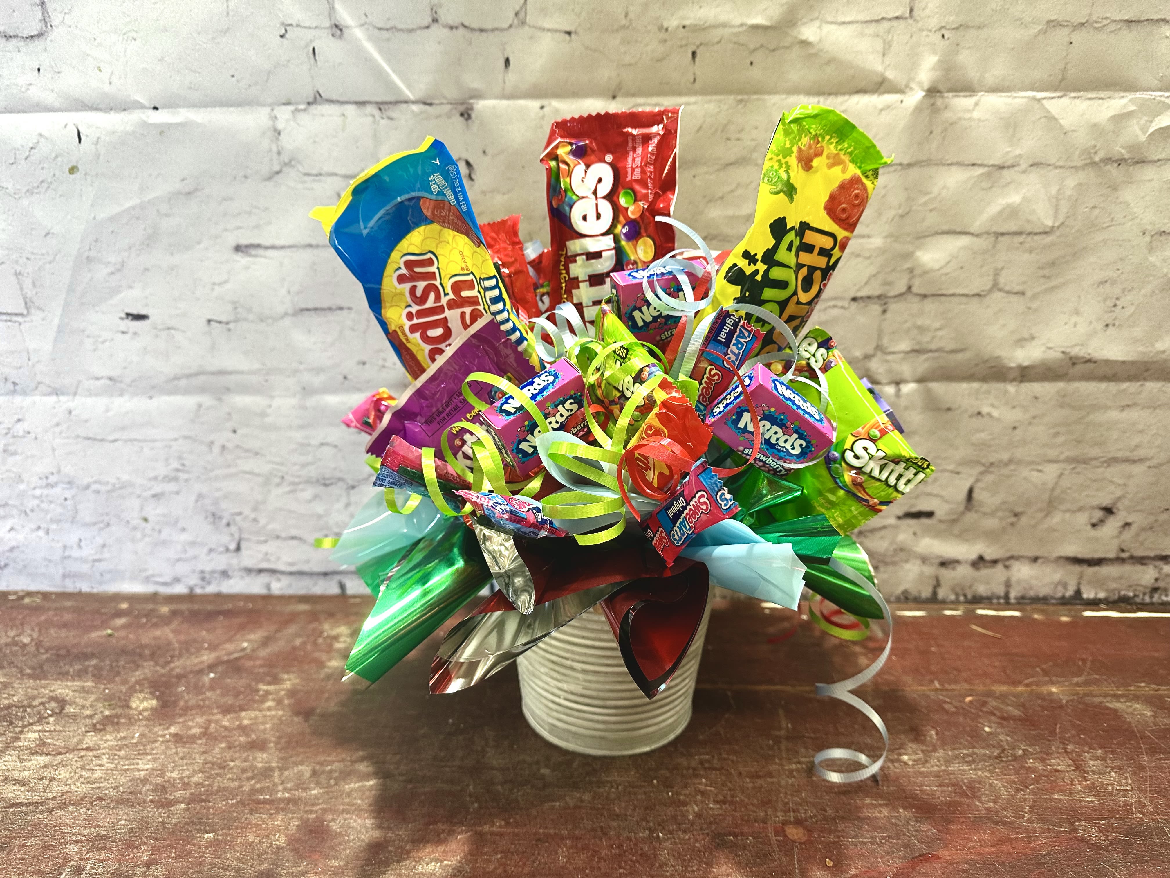 Candy bouquet in a white ribbed container with colorful ribbons