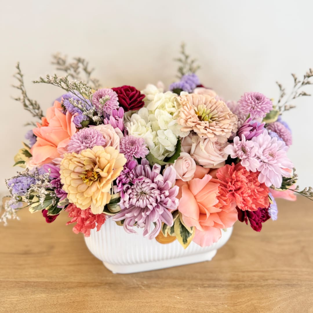 Mixed pastel flower arrangement in a white ceramic vase
