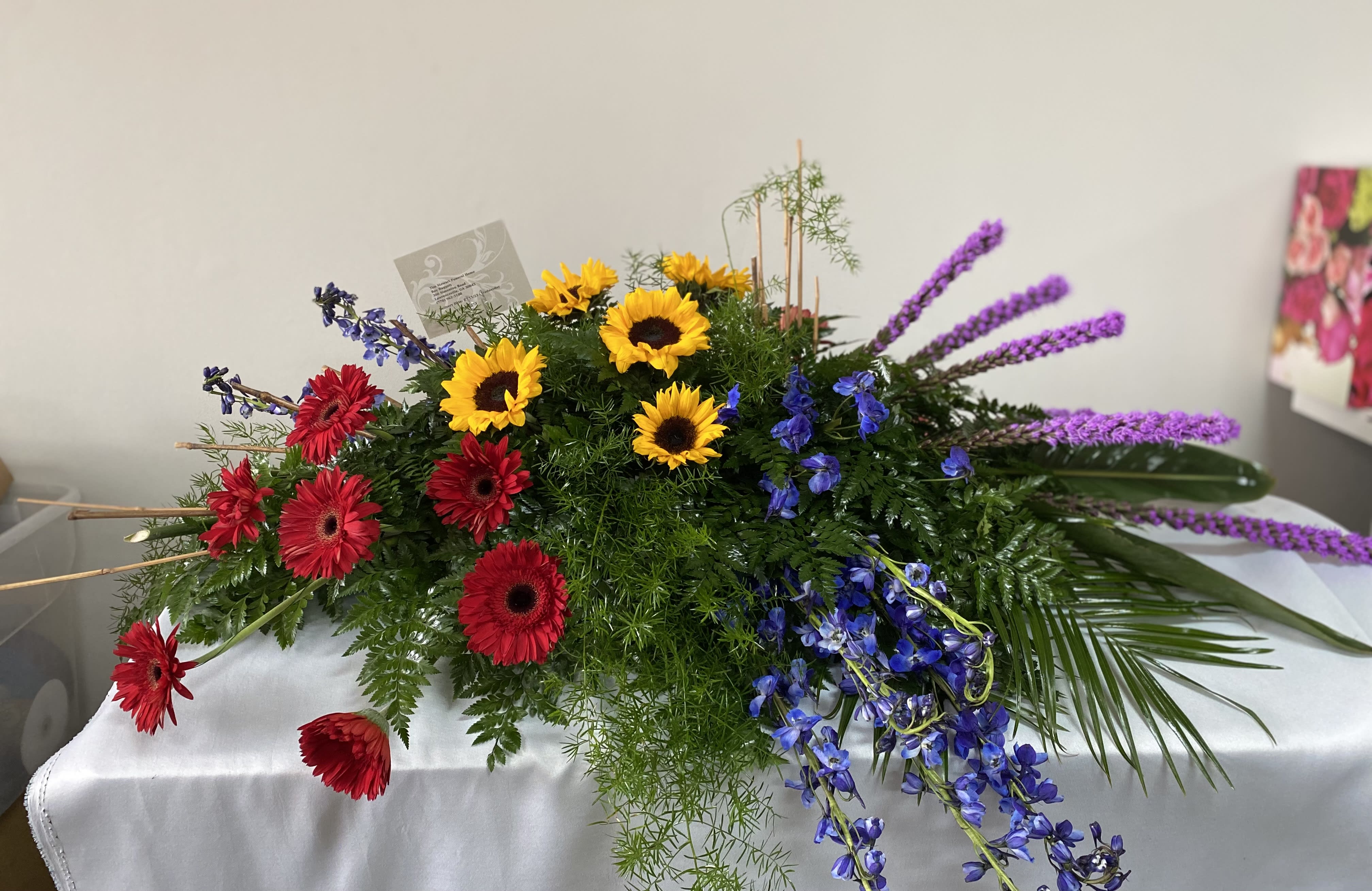 Large mixed floral arrangement with sunflowers, red gerberas, and purple spikes