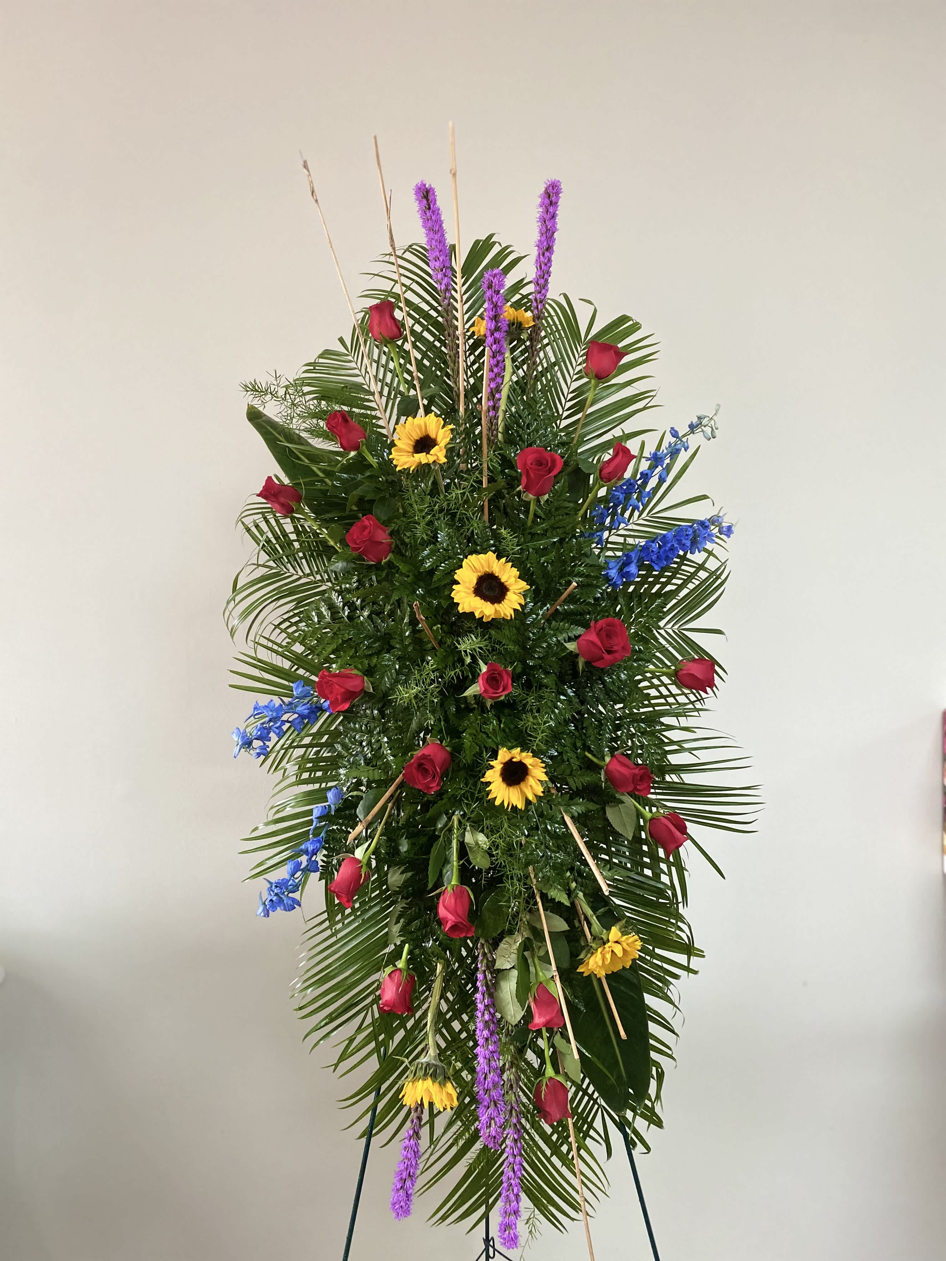Tall standing floral spray with red roses, sunflowers, and purple spikes