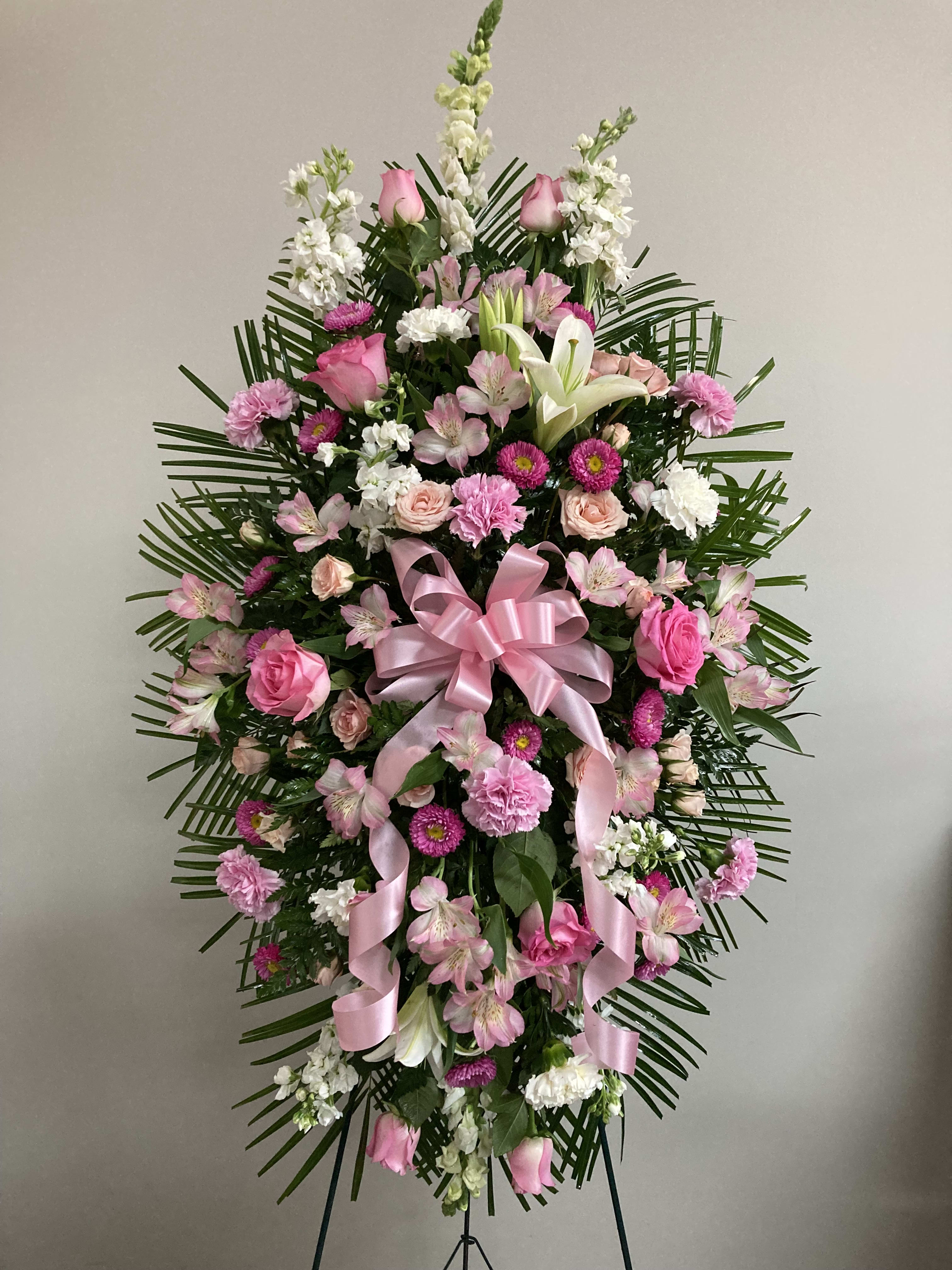 Pink and white funeral spray with roses, lilies, and ribbon