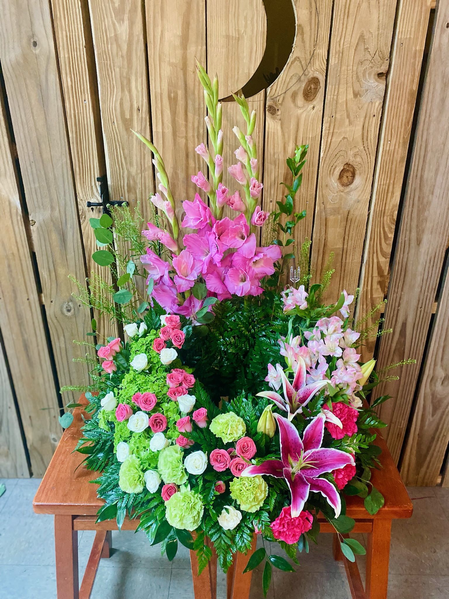 Tall pink floral arrangement with lilies and roses on a wooden table