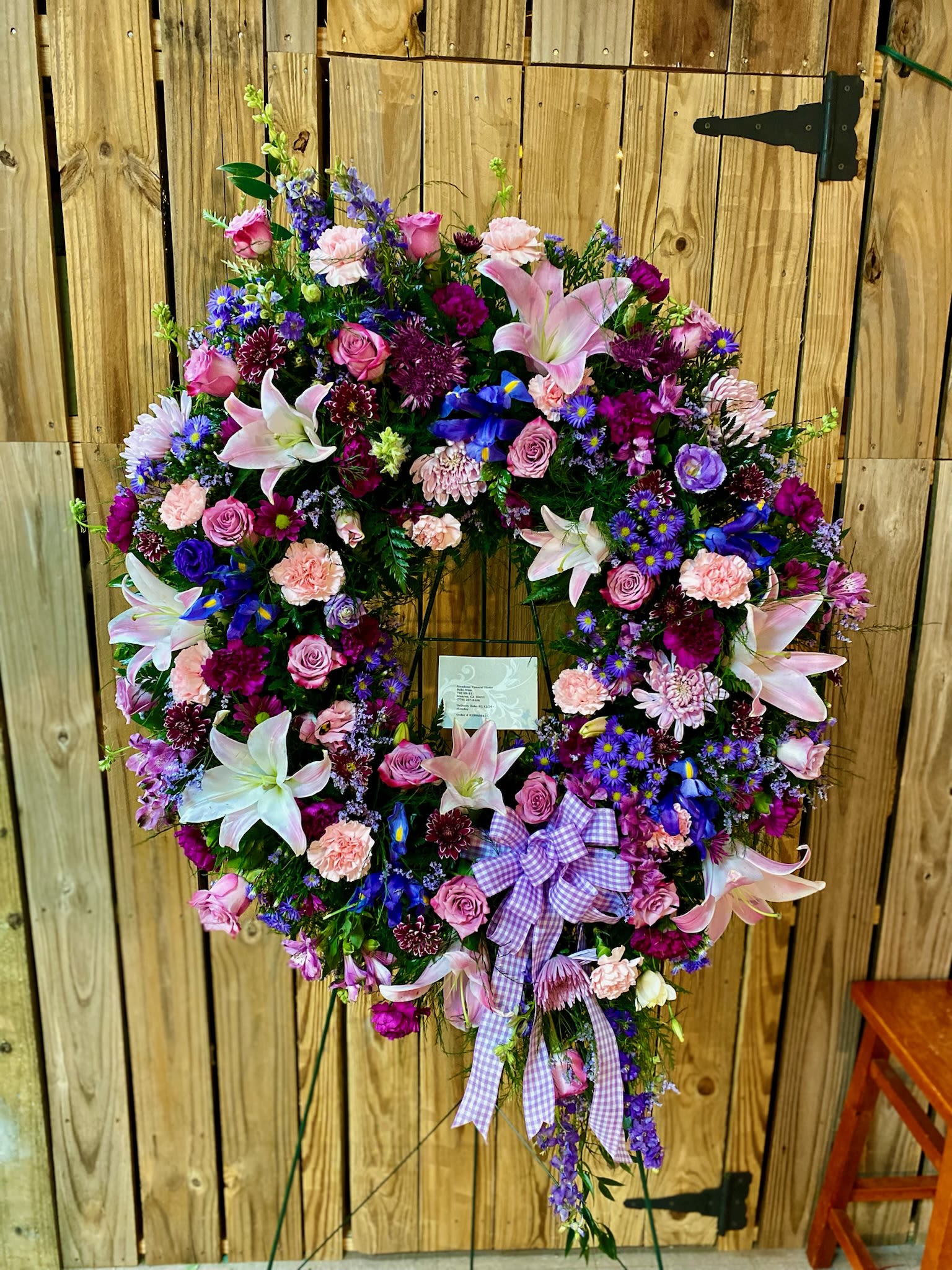 Heart-shaped floral wreath with pink, purple, and white blooms on a stand