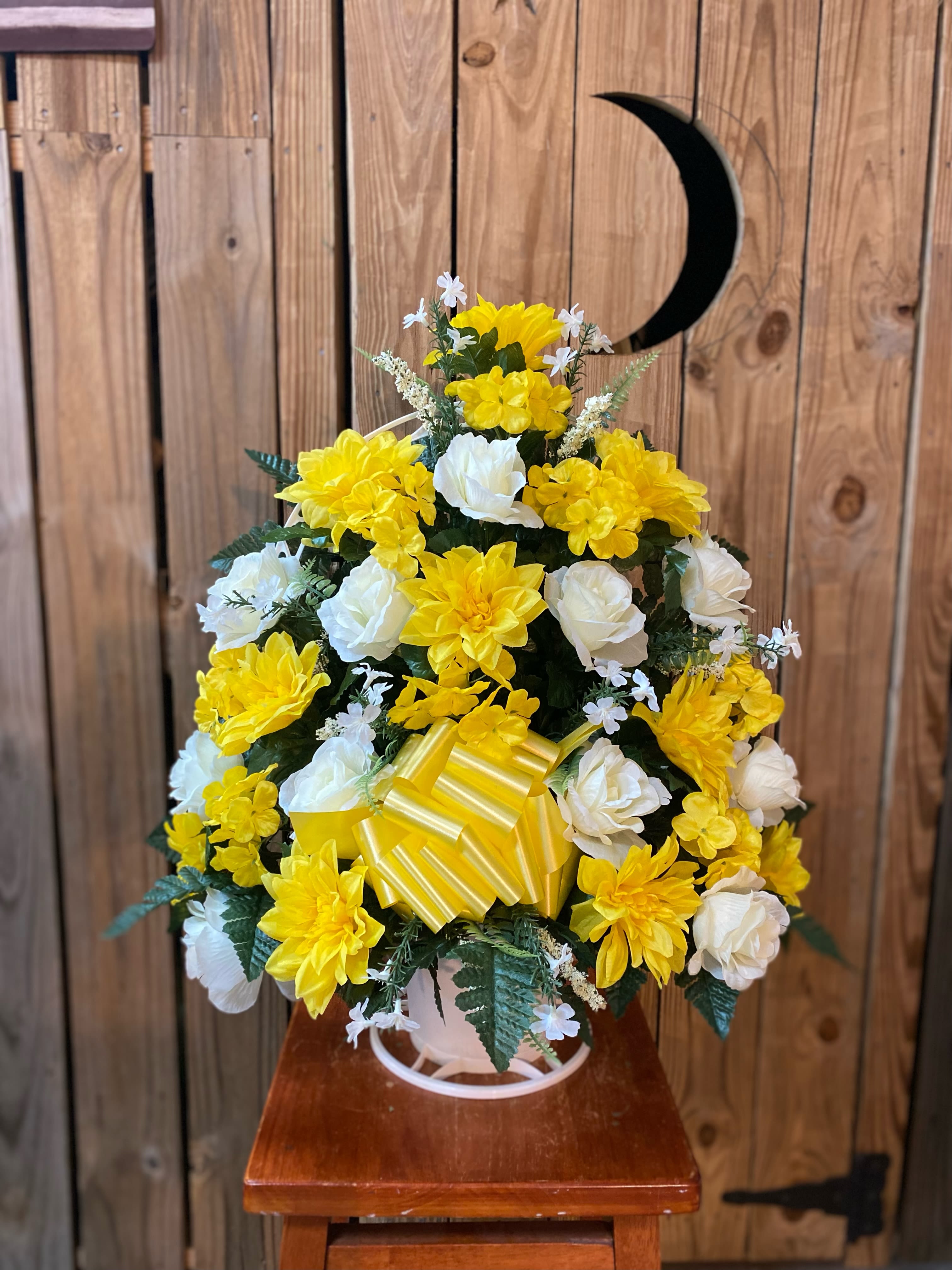 Tall arrangement of yellow and white silk flowers with a yellow striped bow in a white pot.
