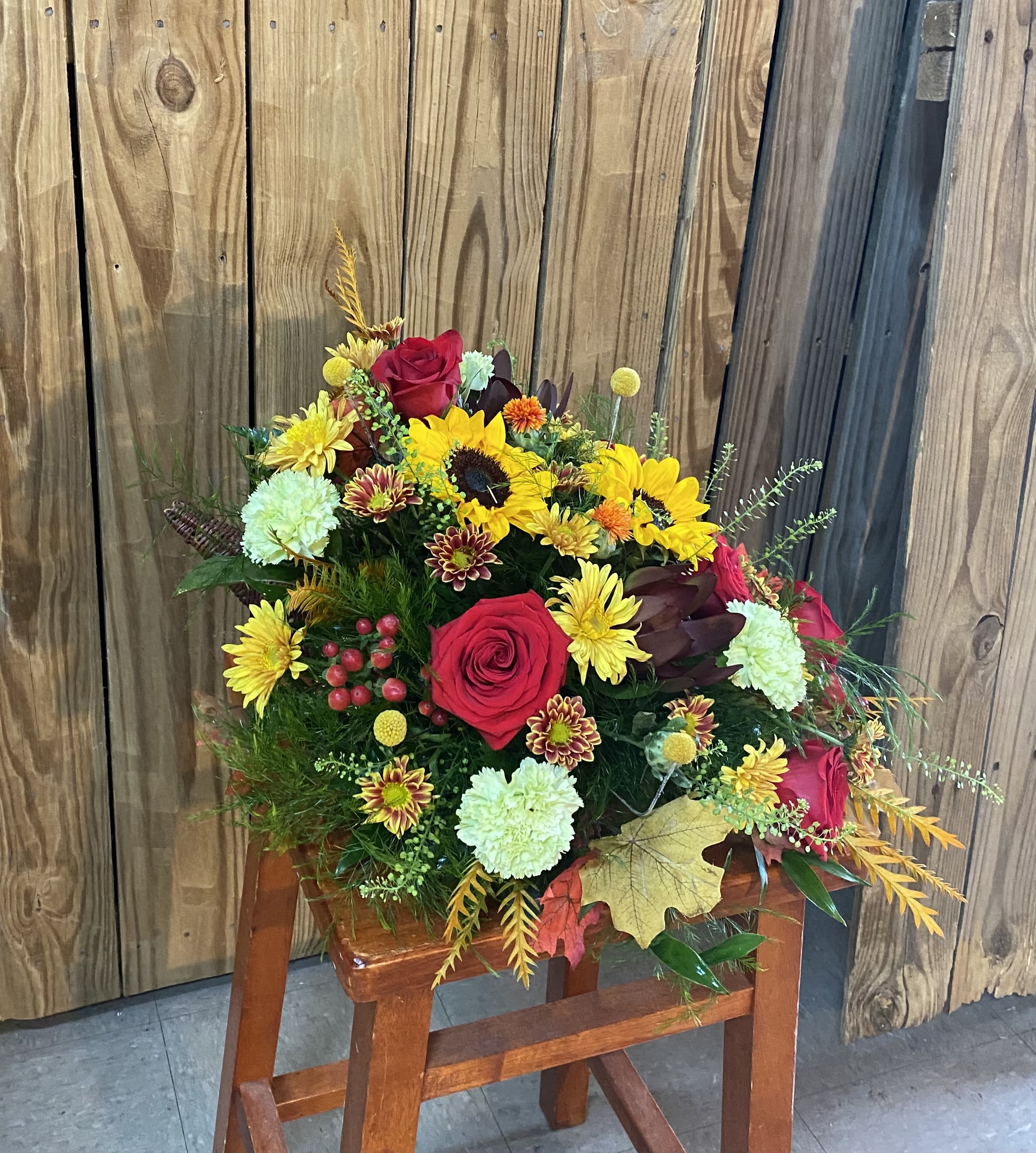Bouquet of red roses, sunflowers, and mixed mums in a rustic arrangement