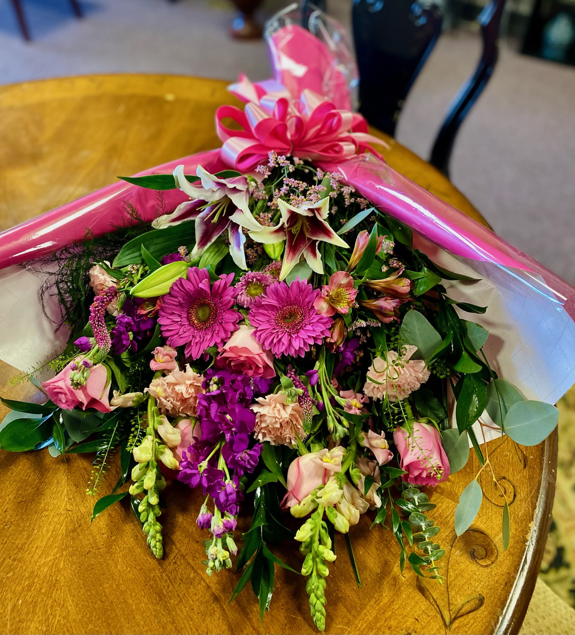 Bouquet of pink and purple flowers wrapped in pink paper with a bow