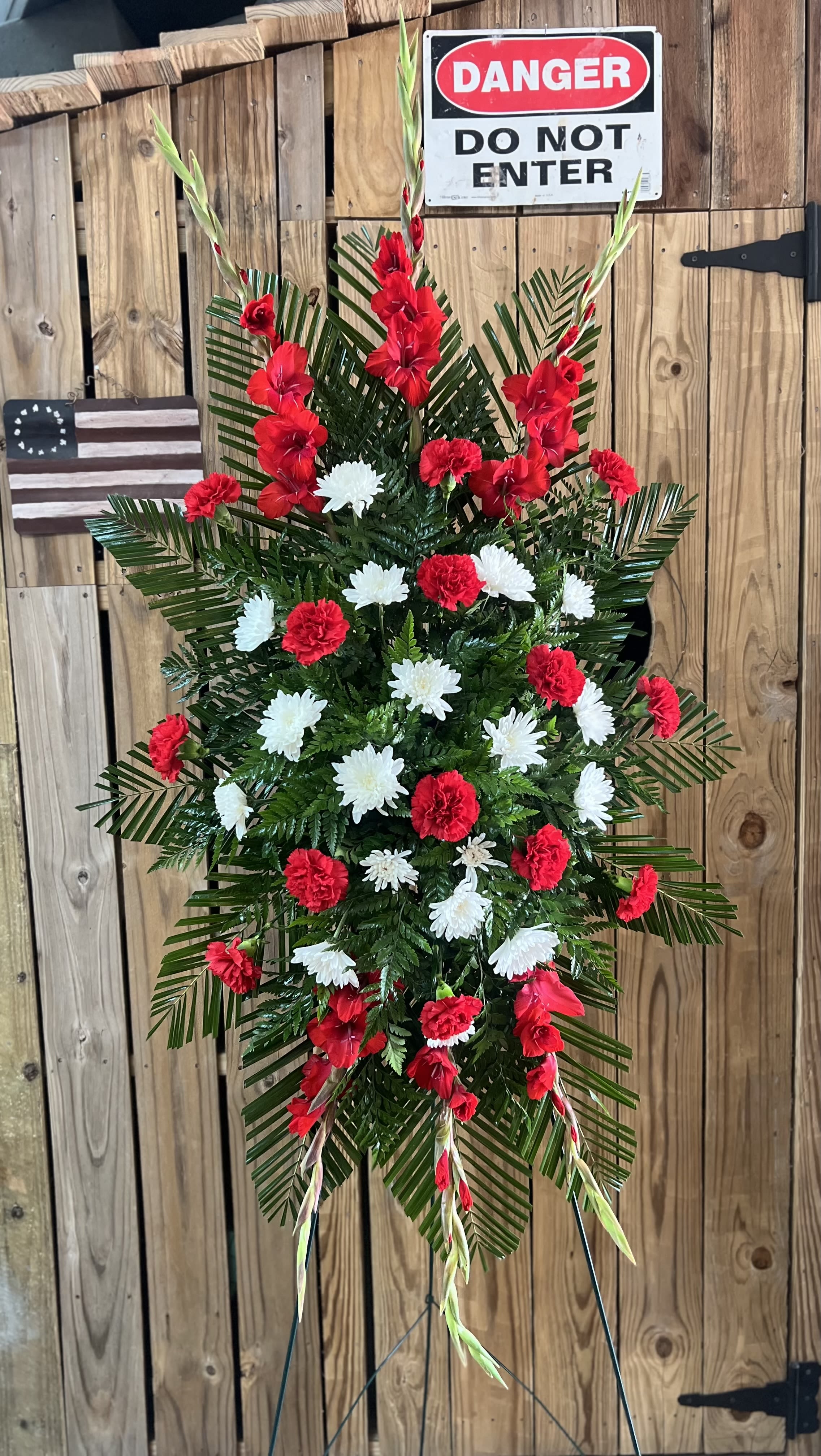 Standing floral spray with red and white flowers on a wire easel